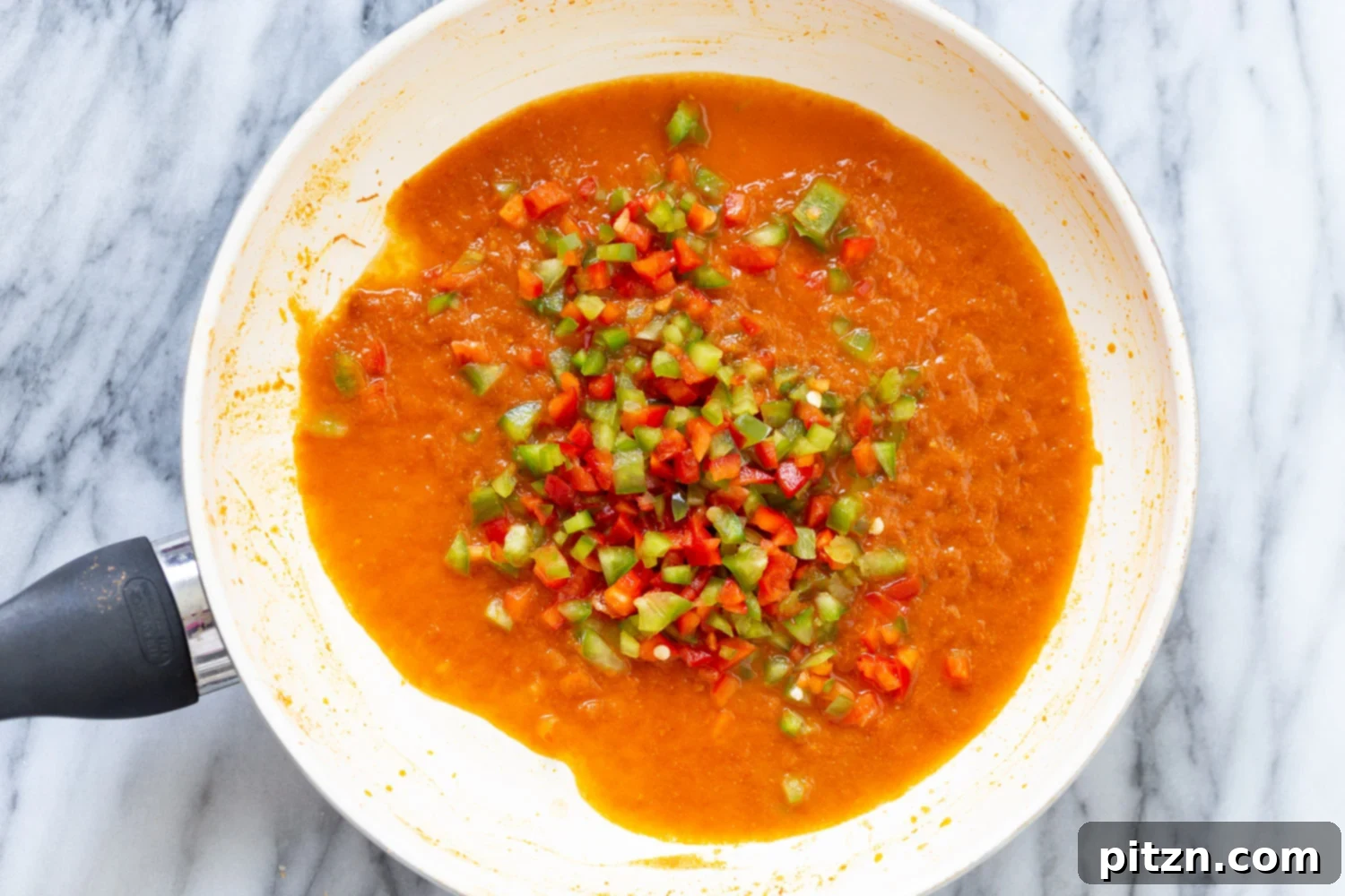 Spanish Cauliflower Rice overhead shot of a saucepan with tomato sauce and diced bell pepper for making Spanish cauliflower rice