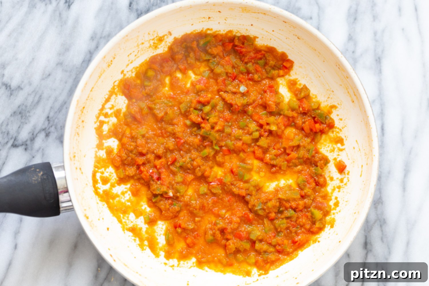 Spanish Cauliflower Rice overhead shot of reduced tomato and bell pepper sauce in a white sauce pan