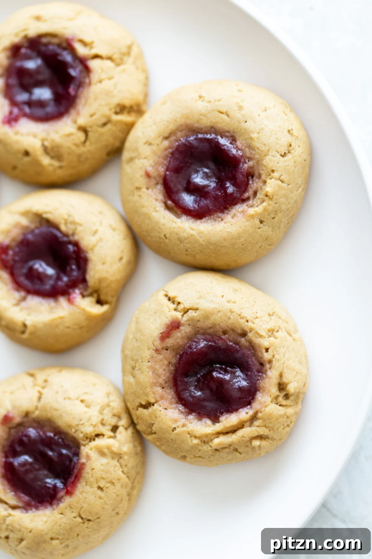 overhead shot of vegan pb & j thumbprint cookies on a white plate