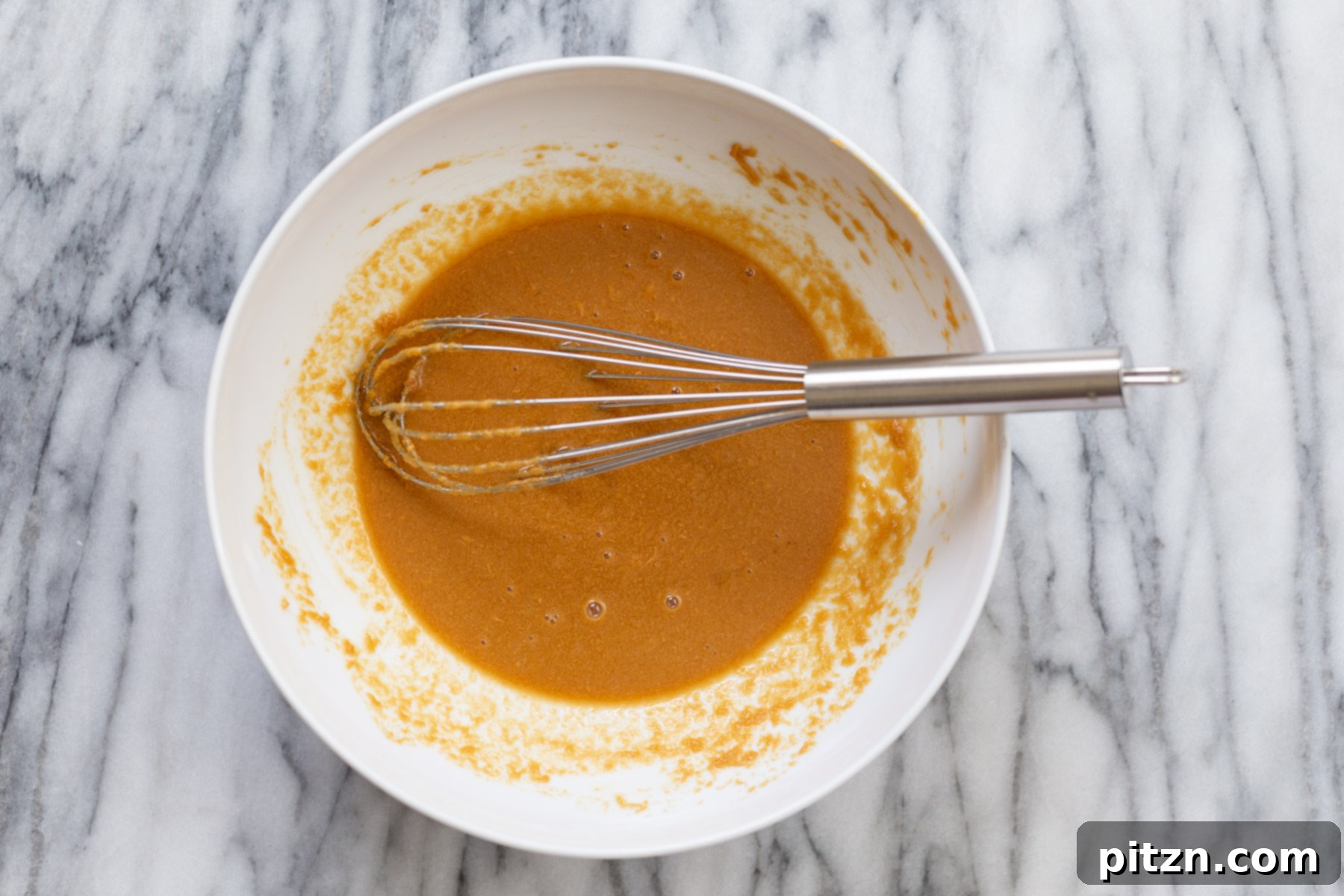 ingredients being mixed in a white bowl to make peanut butter thumbprint cookies