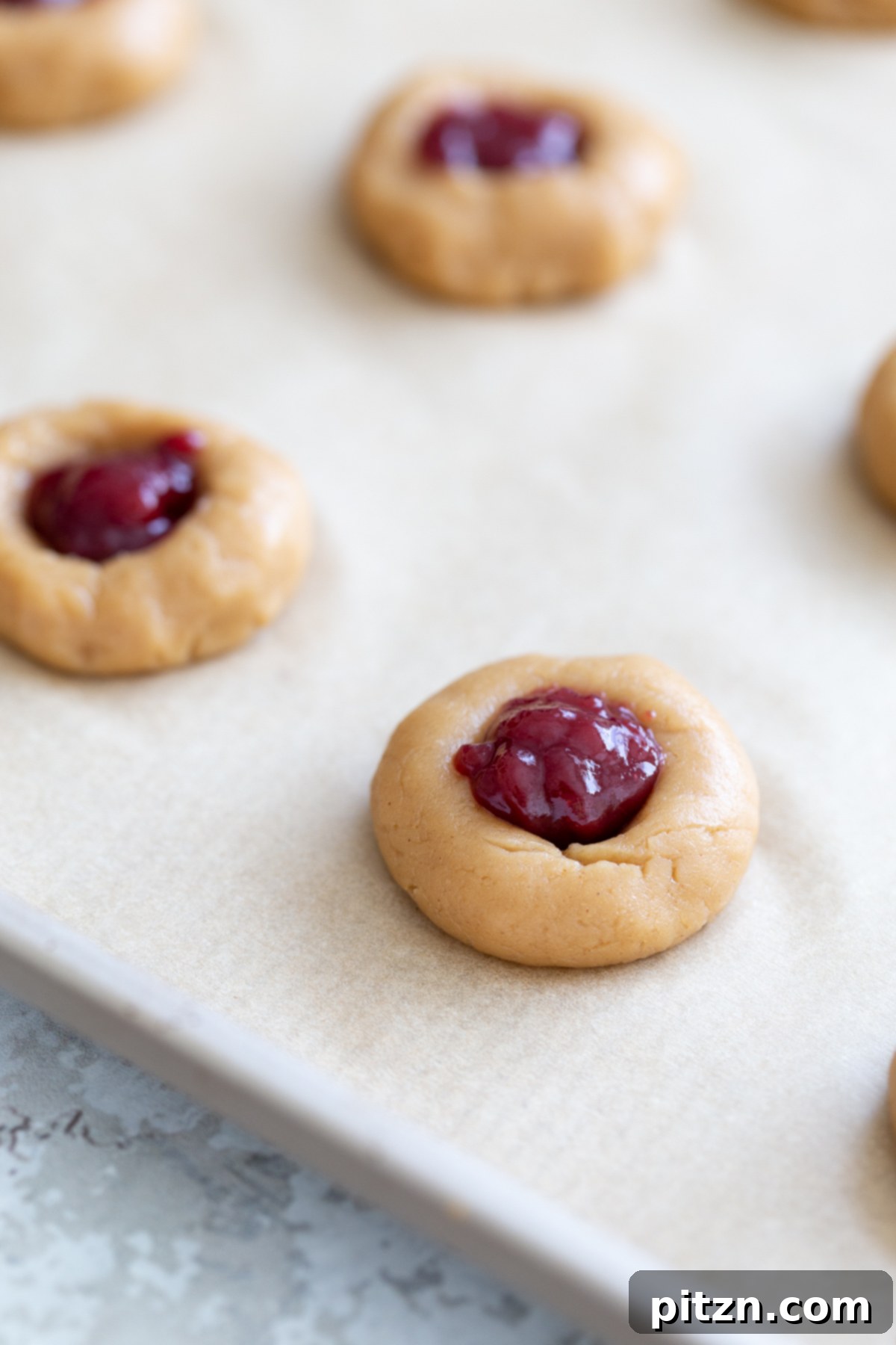 jam-filled pb&j vegan thumbprint cookies on a cookie sheet ready to be baked