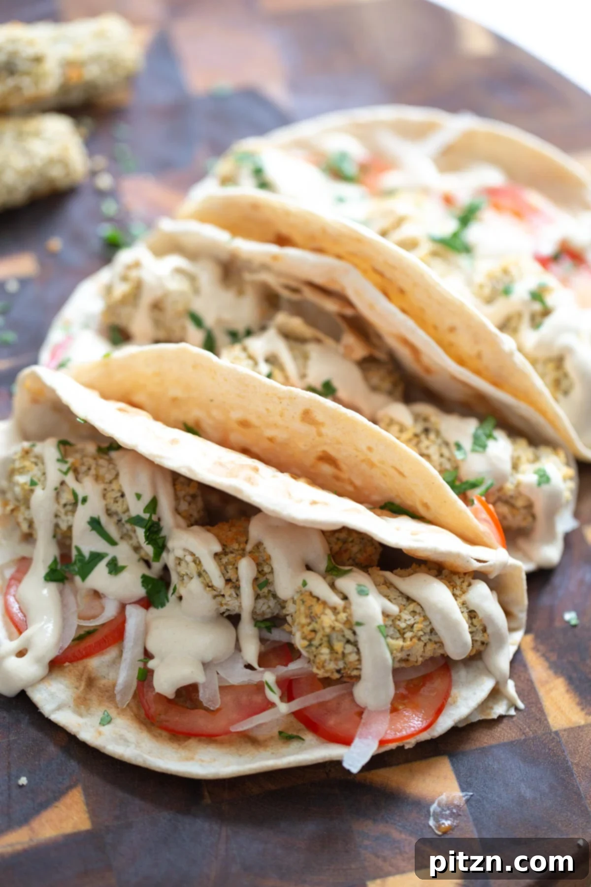 three vegan wraps filled with vegan chickpea quinoa croquettes and drizzled with tahini sauce