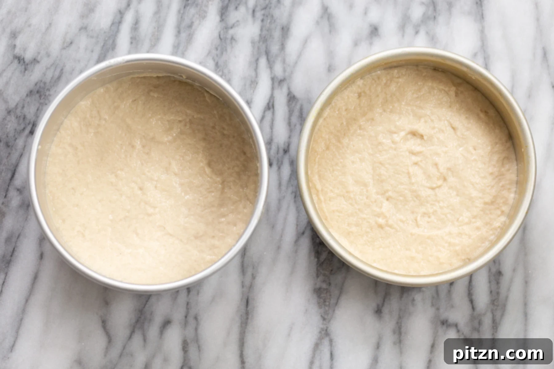 Two springform pans filled with vegan white cake batter, ready for baking.