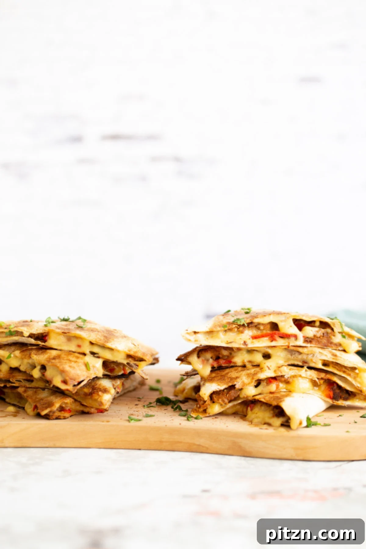 two stacks of quesadillas filled with vegan walnut taco meat on a chopping board