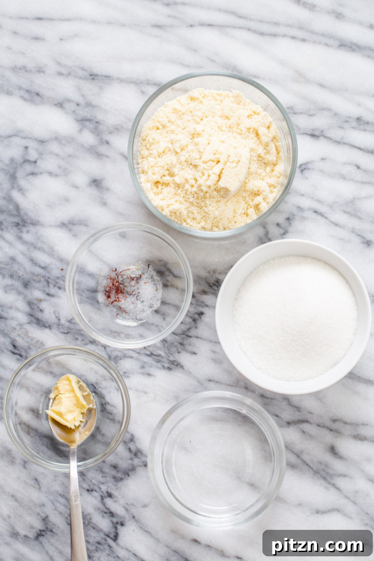 Rich Plant-Based Almond Burfi 3 A collection of the four essential ingredients for vegan almond burfi: sugar, water, saffron, and almond flour, laid out neatly for preparation.
