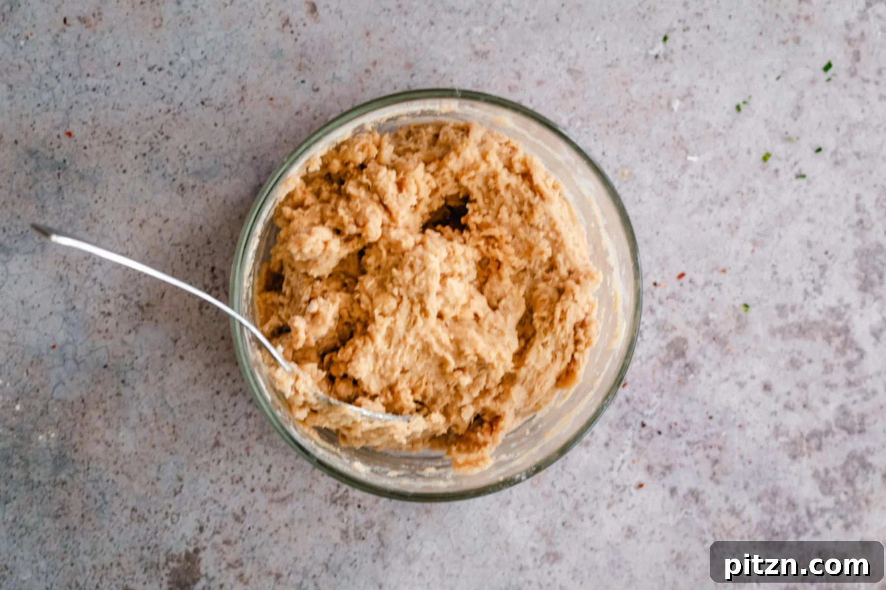 A small glass bowl holds the sticky, stiff vegan churro biscotti dough, showcasing its texture before shaping.
