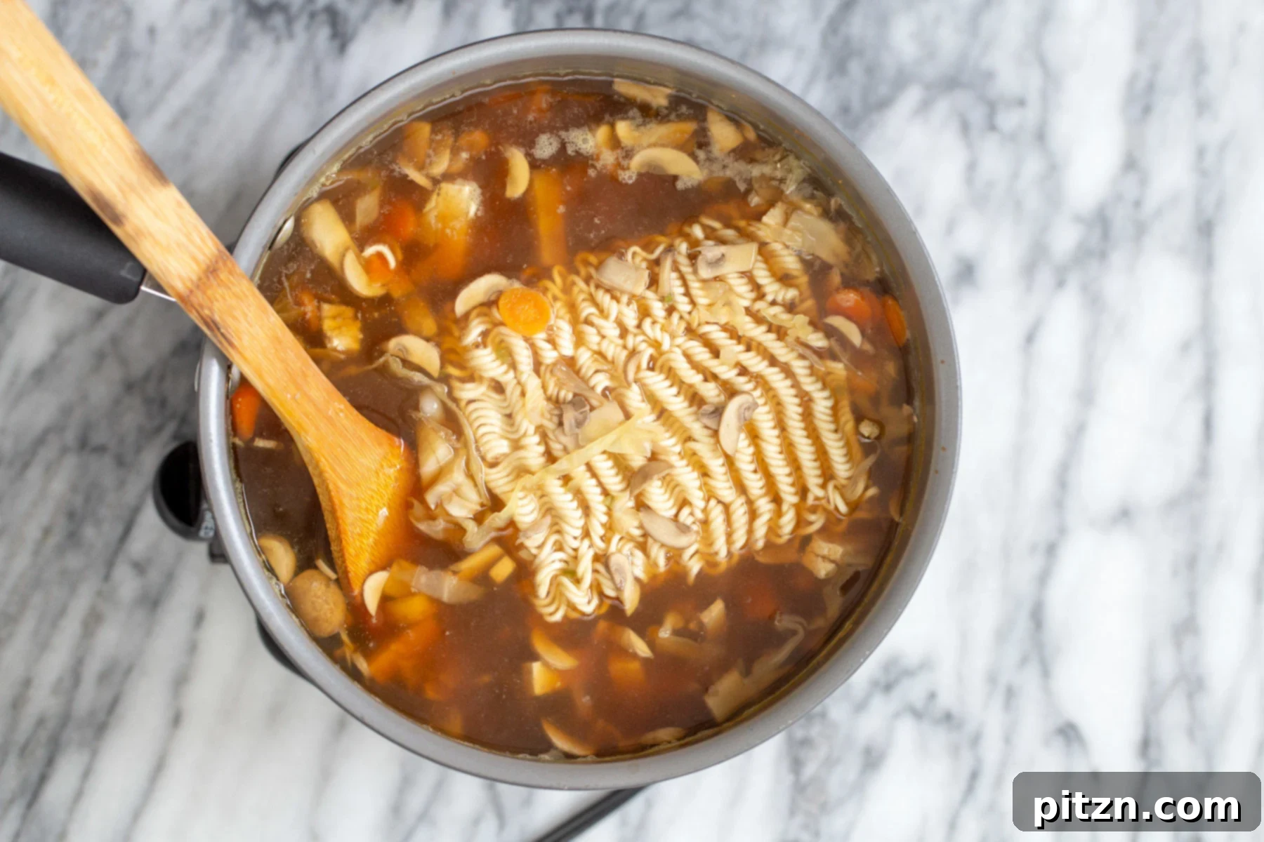 Vegan Hot and Sour Ramen Bowl 10 Ramen noodles are carefully added to a pot of boiling vegan hot and sour soup, ready to be incorporated into the hearty broth.