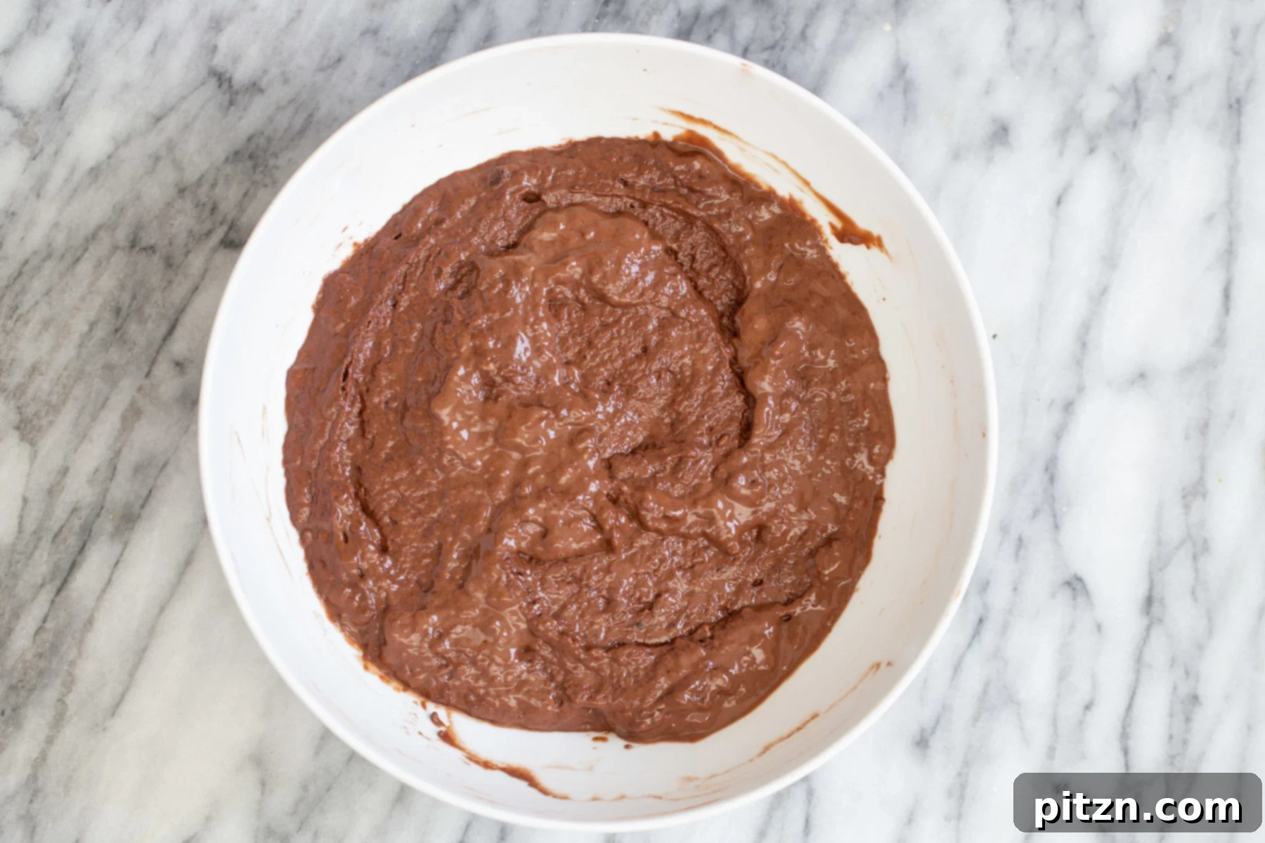 Perfectly Blended Vegan German Chocolate Cake Batter Smooth, glossy vegan chocolate cake batter in a pristine white mixing bowl, perfectly blended and ready for the next step of layering with the caramel swirl.