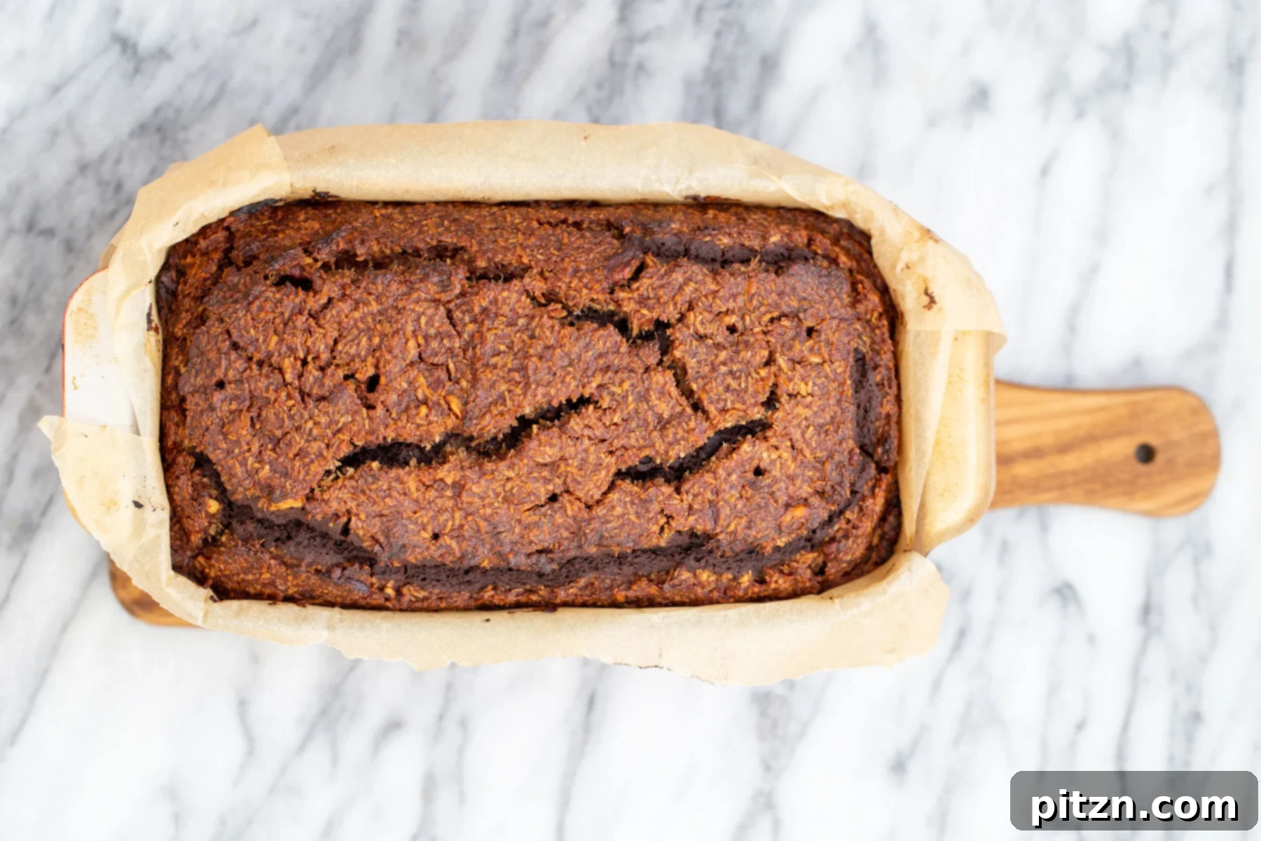 Coconut Pecan Chocolate Loaf 7 An inviting overhead shot of a freshly baked Vegan German Chocolate Loaf Cake, showcasing its perfectly golden-brown top and the subtle hints of the caramel swirl. The cake rests in its loaf pan, just out of the oven.