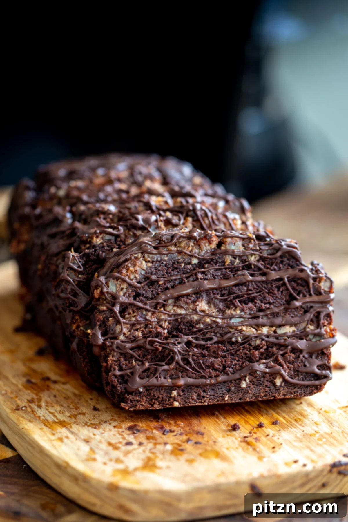 Coconut Pecan Chocolate Loaf 8 A close-up shot of the freshly baked Vegan German Chocolate Loaf Cake, still warm on a wire rack, being elegantly drizzled with melted dark chocolate from above. The chocolate cascades beautifully over the top, enhancing its rich appearance.