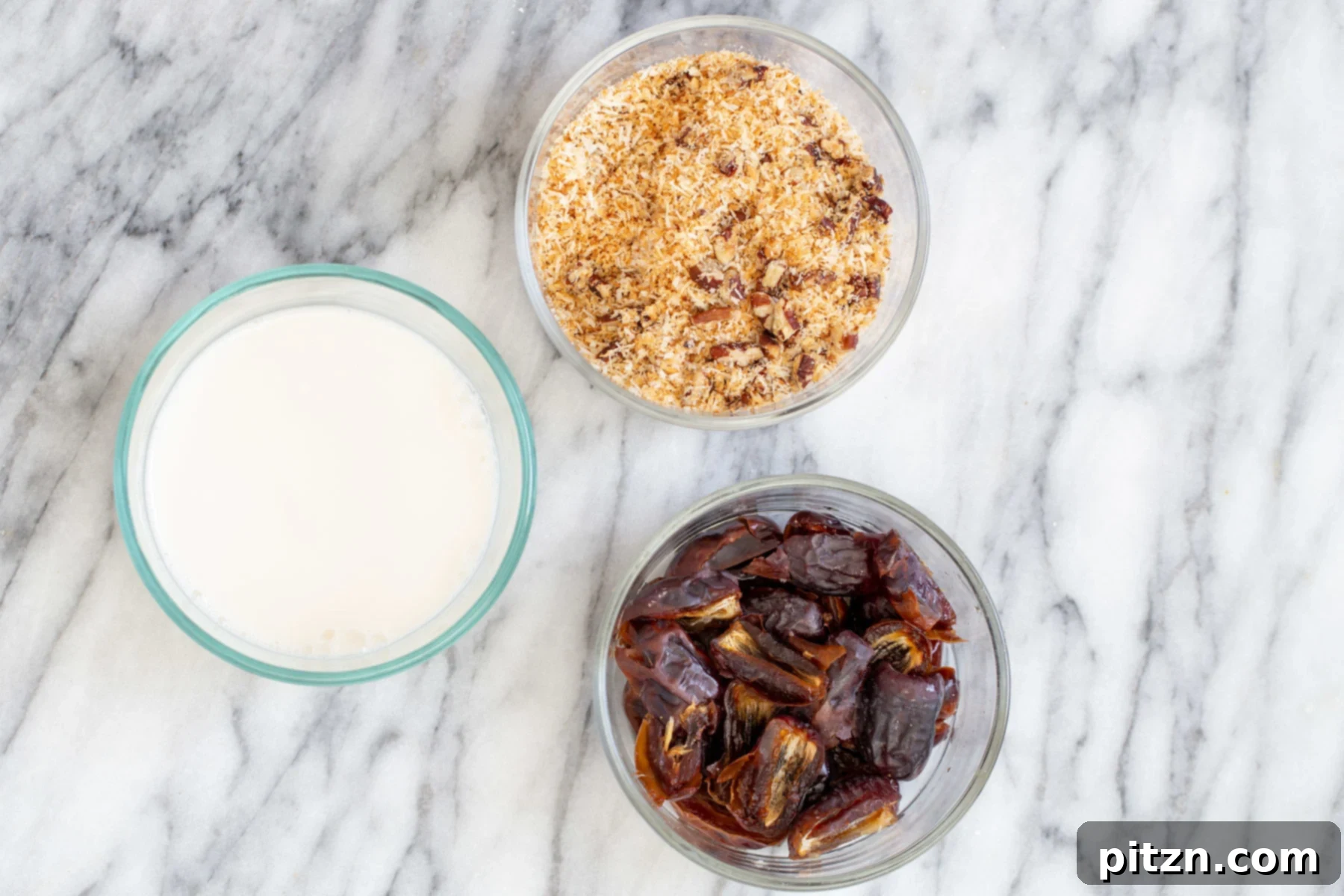 Coconut Pecan Chocolate Loaf 2 A selection of ingredients for the coconut pecan caramel swirl, including plump, soaked dates, a measuring cup of non-dairy milk, a small bowl of maple syrup, and separate bowls of toasted pecans and shredded coconut.