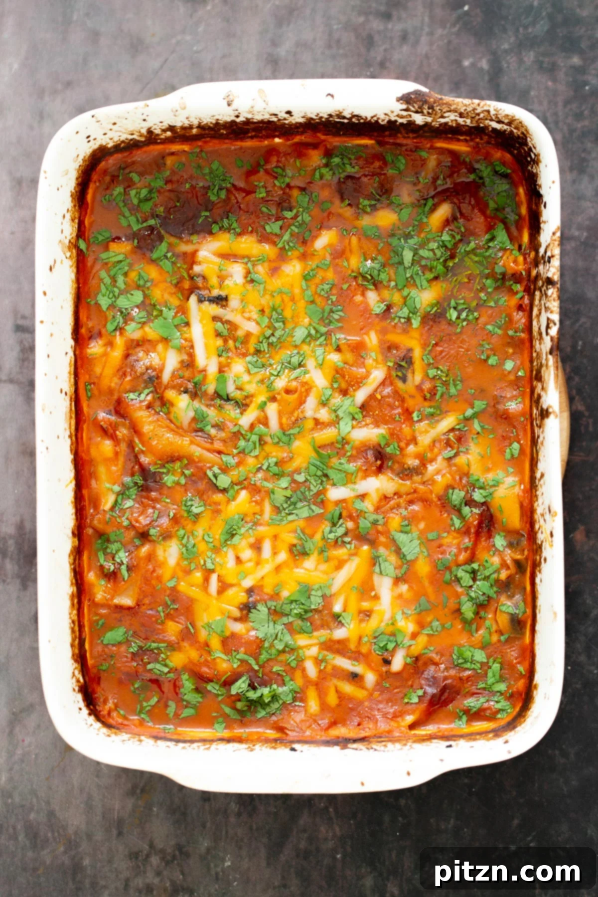 A freshly baked casserole dish of vegan butter chicken lasagna, garnished generously with chopped cilantro.