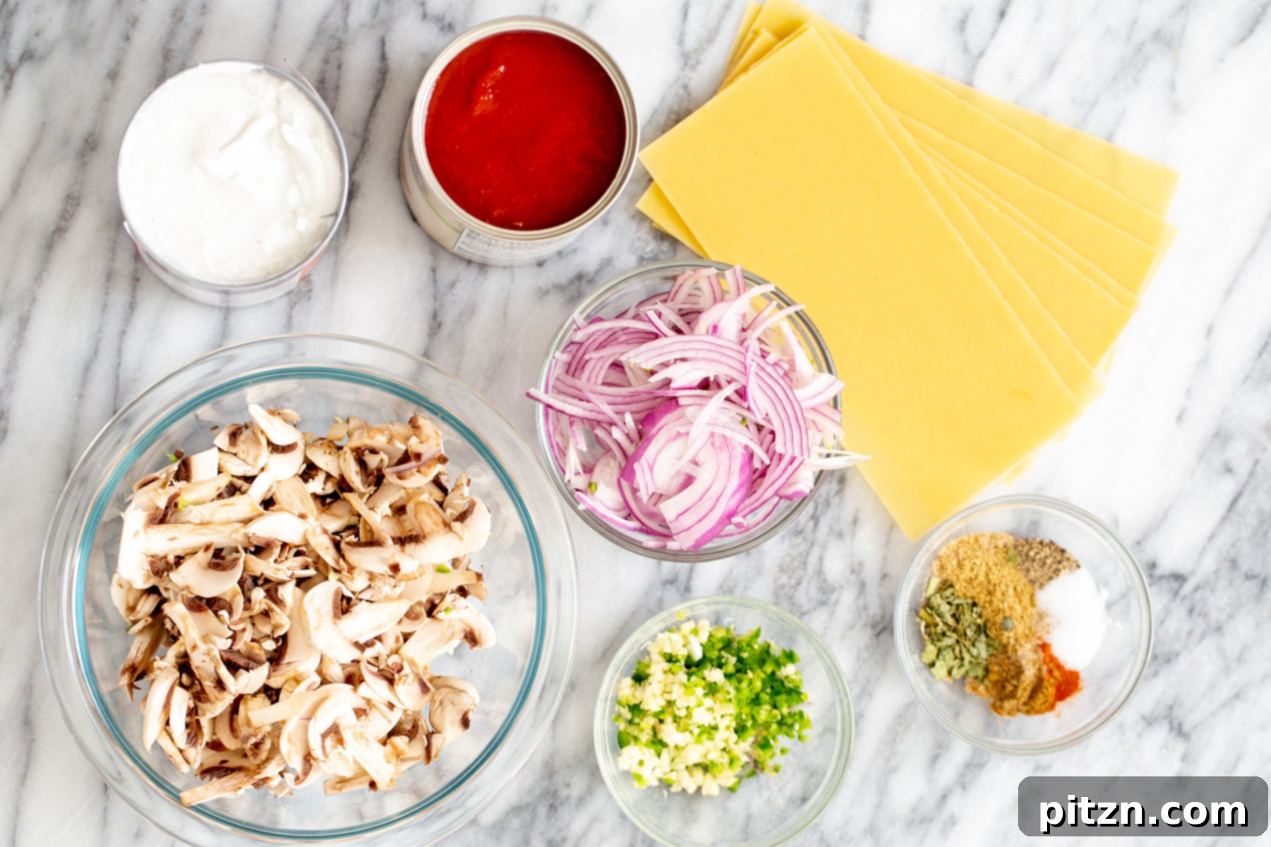 A flat lay shot of all the individual ingredients needed to make vegan butter chicken lasagna bake, including spices, vegetables, and pasta.