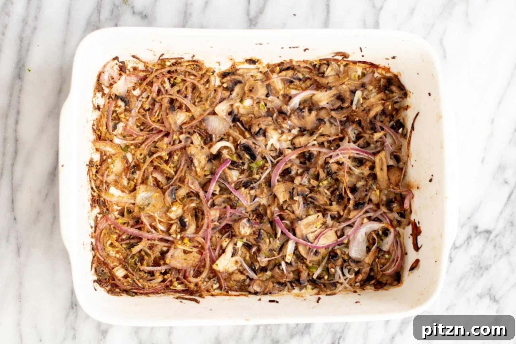 Crispy golden-brown mushrooms and caramelized onions after being baked in a casserole dish.