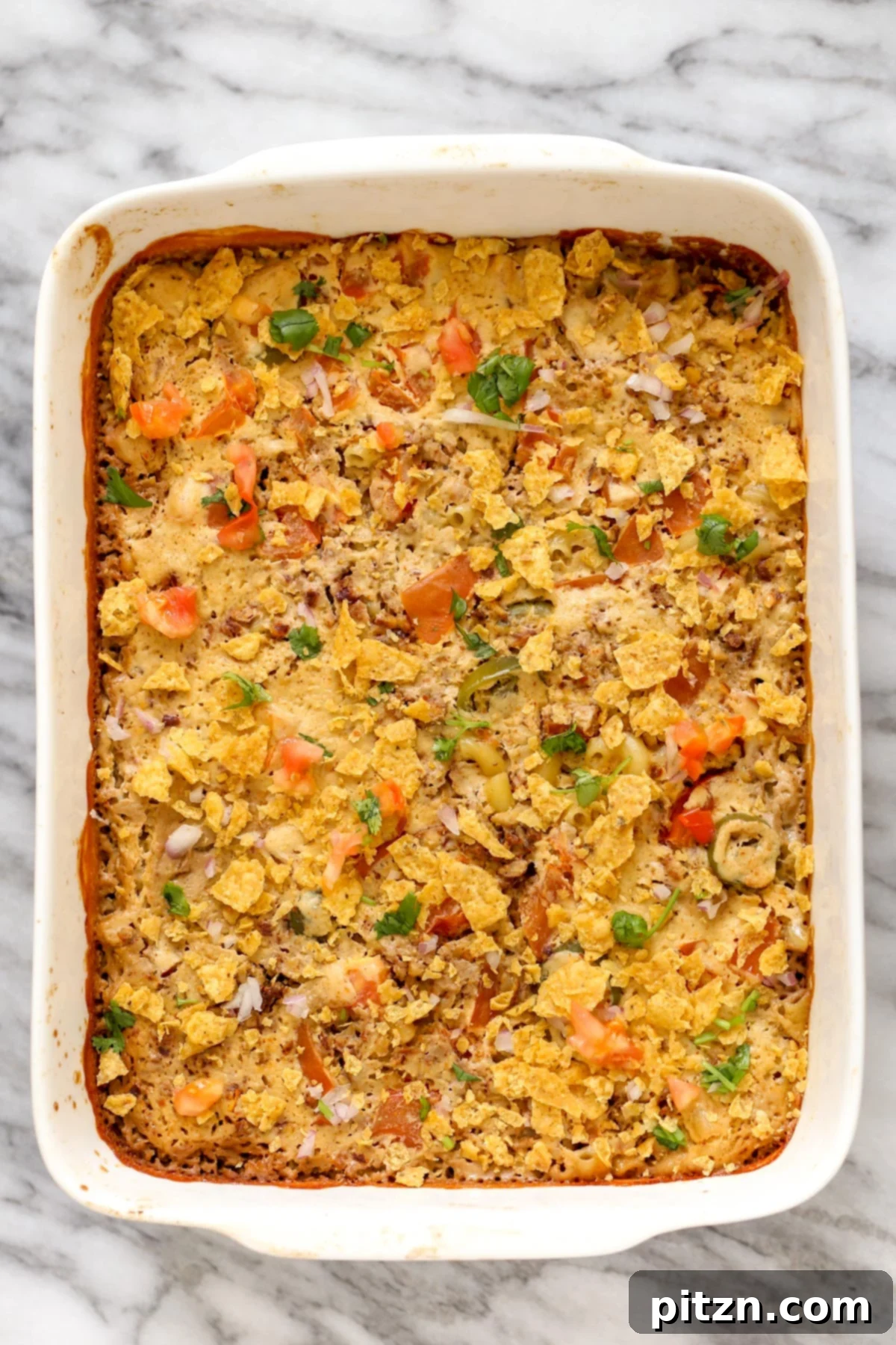 a casserole dish with vegan mac and cheese bake topped with crushed tortilla chips 