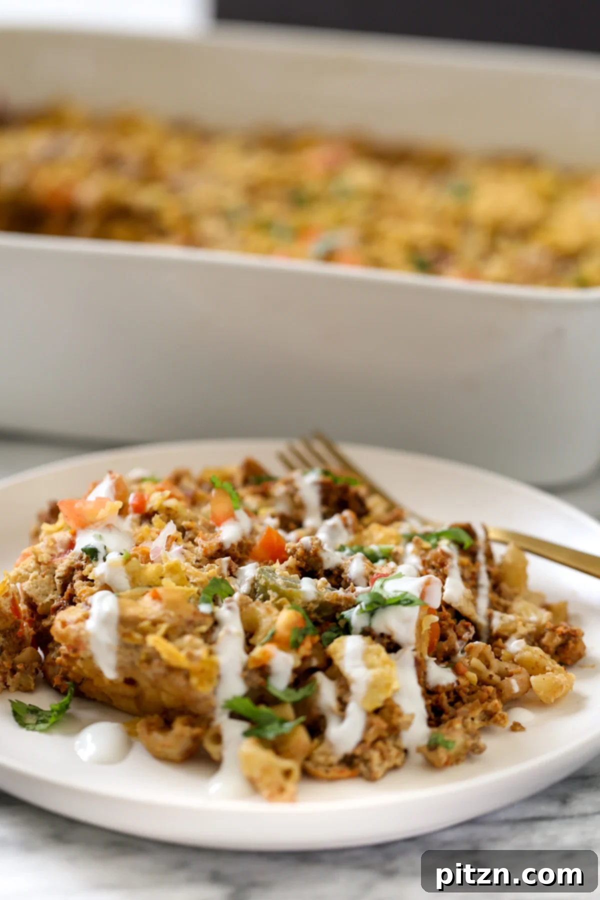 a serving of vegan mac and cheese taco bake drizzled with vegan sour cream