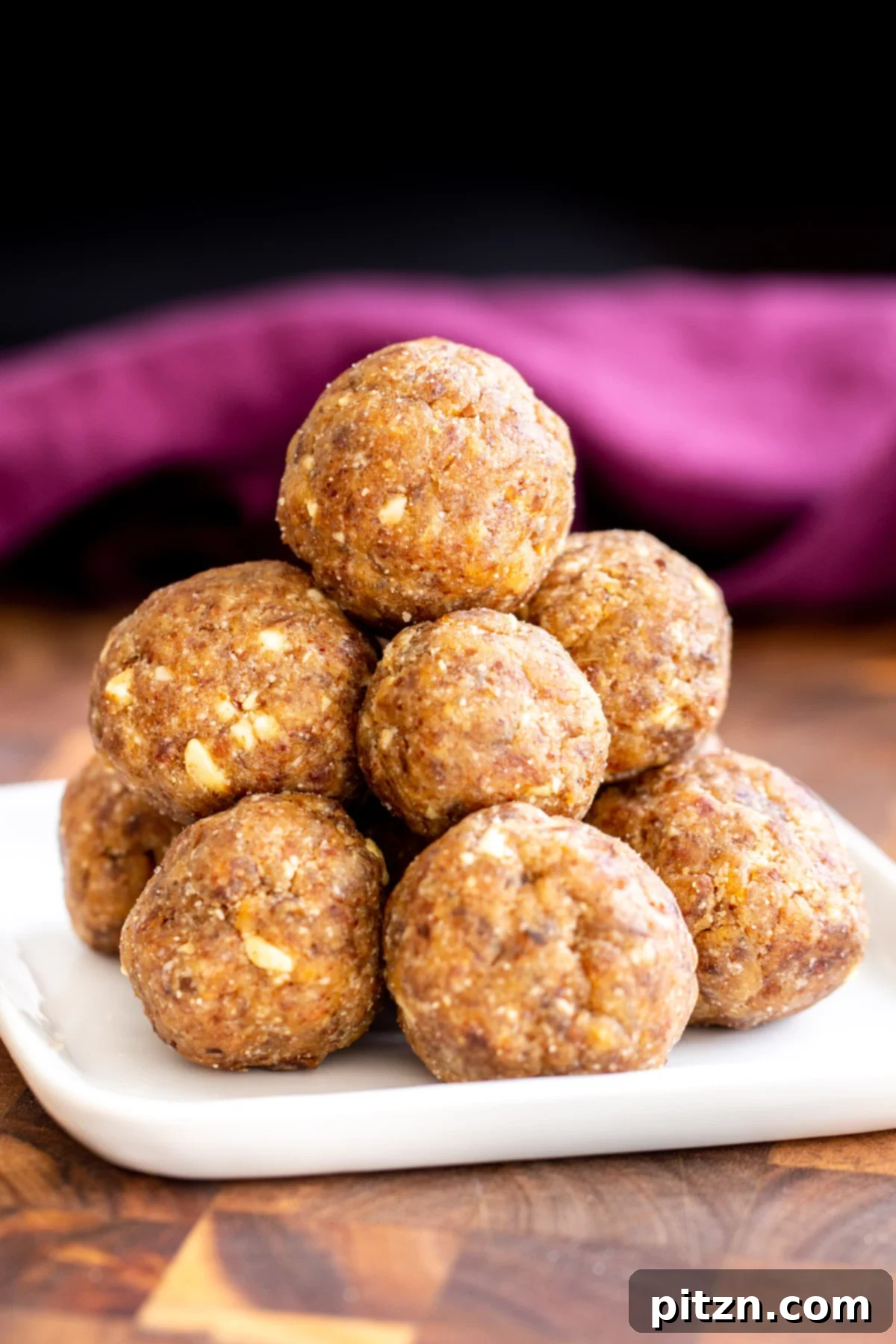 date ladoo A close-up of a single vegan whole wheat date ladoo, beautifully presented on a small white plate.