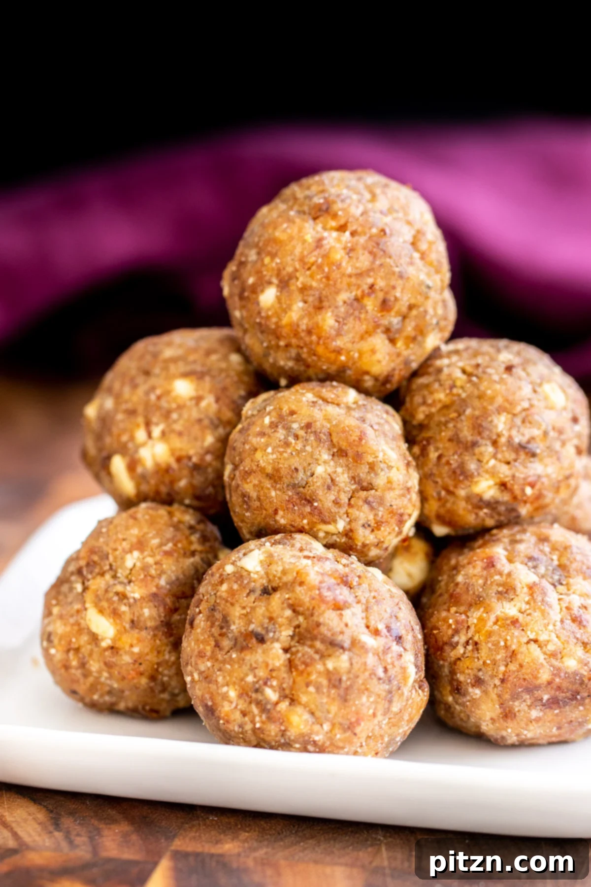 date ladoo Elegantly stacked Indian Date Ladoos presented on a pristine white plate, showcasing their inviting texture.