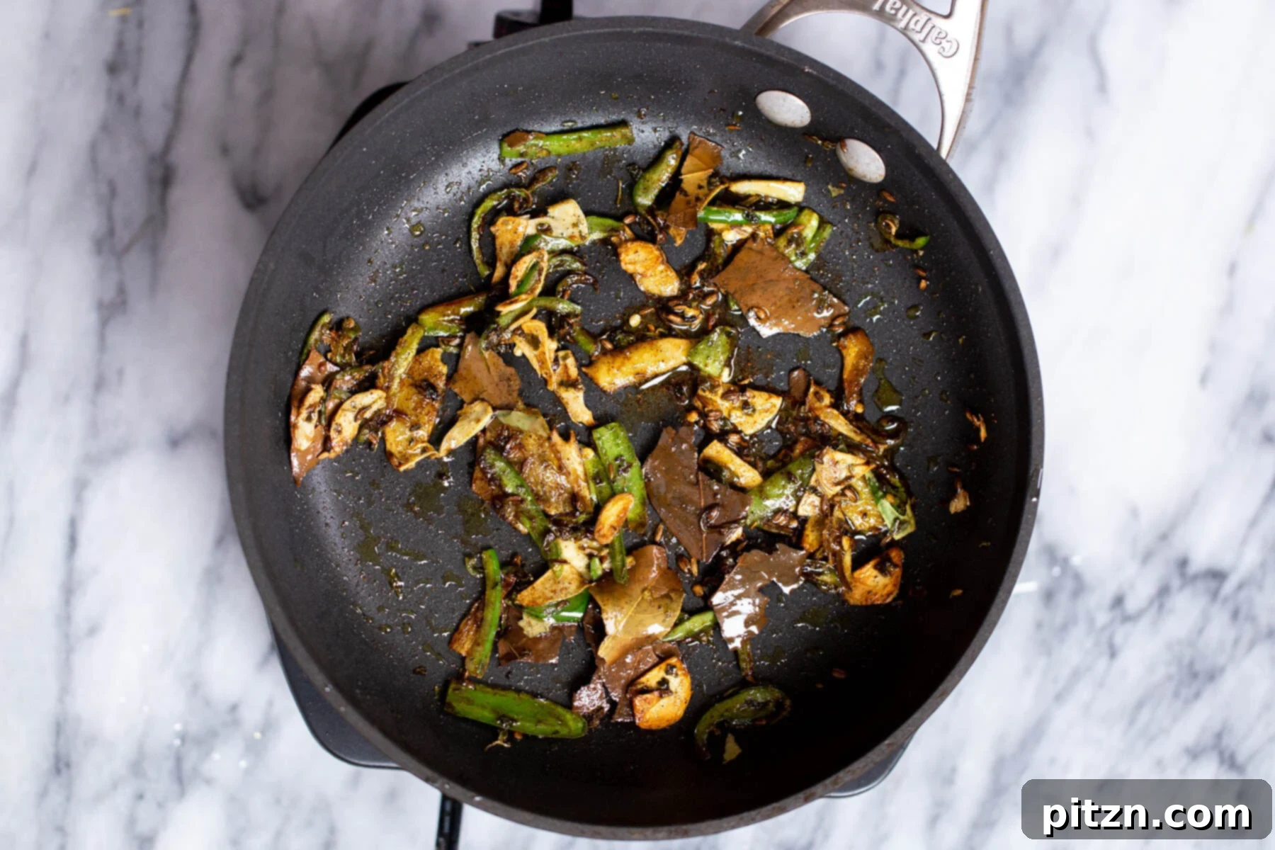 tempered green chile and ginger in a black sauteeing pan