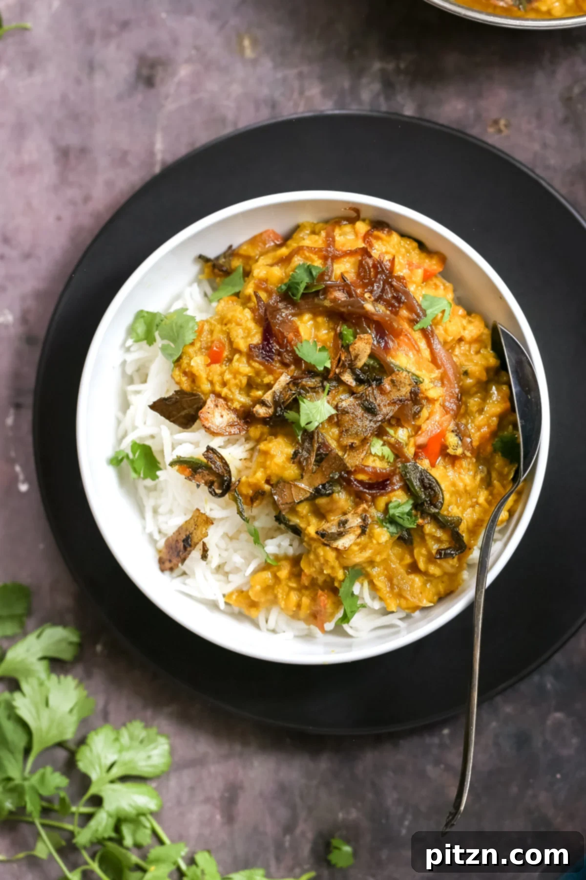 masoor dal tadka served over rice sprinkled with cilantro 