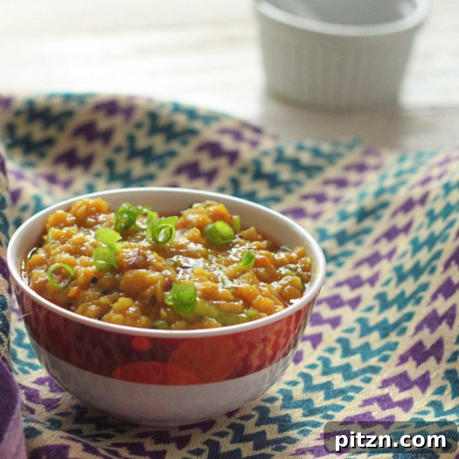 A close-up of cooked red lentils, showing their soft, creamy texture in a pot, ready to be tempered with spices.
