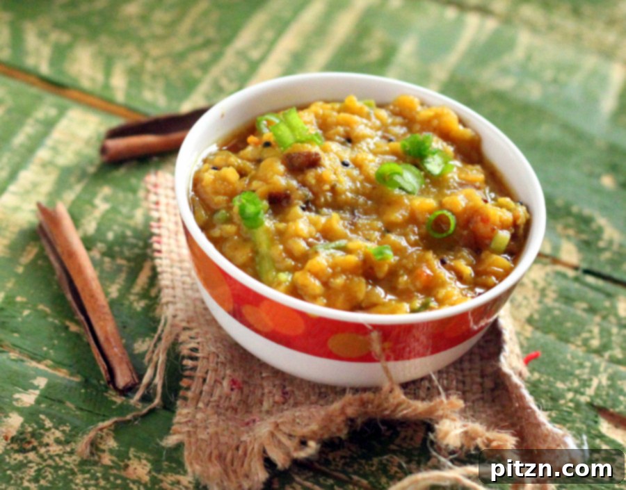 A beautifully presented bowl of Masoor Daal, garnished with fresh cilantro and a lime wedge, ready to be enjoyed.