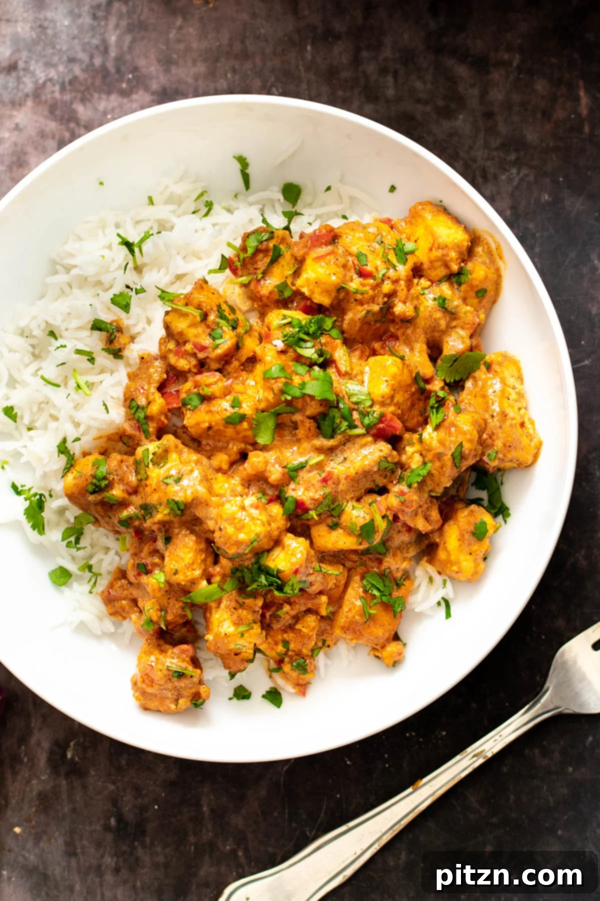Vegan Tofu Rogan Josh 2 A vibrant plate of vegan Tofu Rogan Josh served alongside fluffy basmati rice, garnished with fresh cilantro.