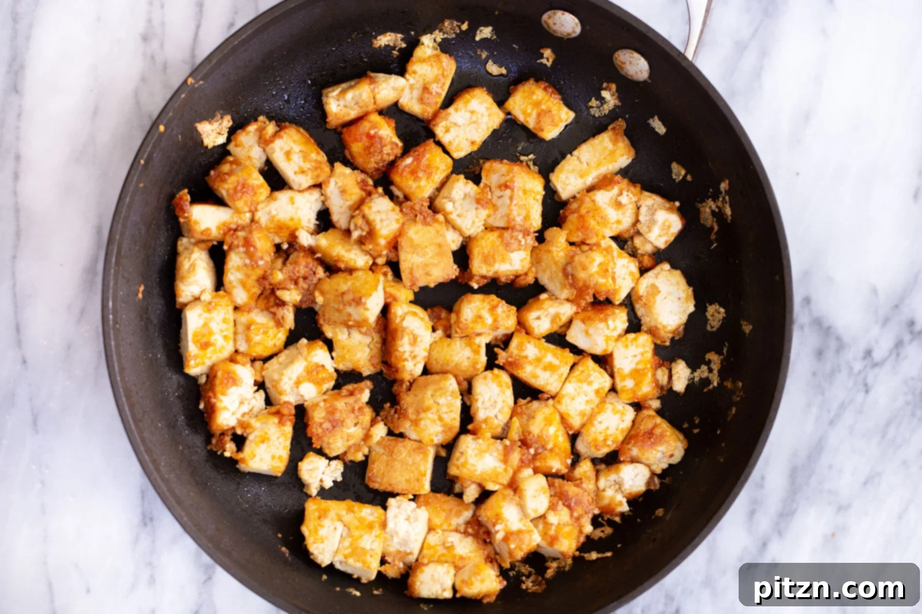 Vegan Tofu Rogan Josh 10 Marinated tofu cubes frying in a sauté pan, turning golden brown and crispy.