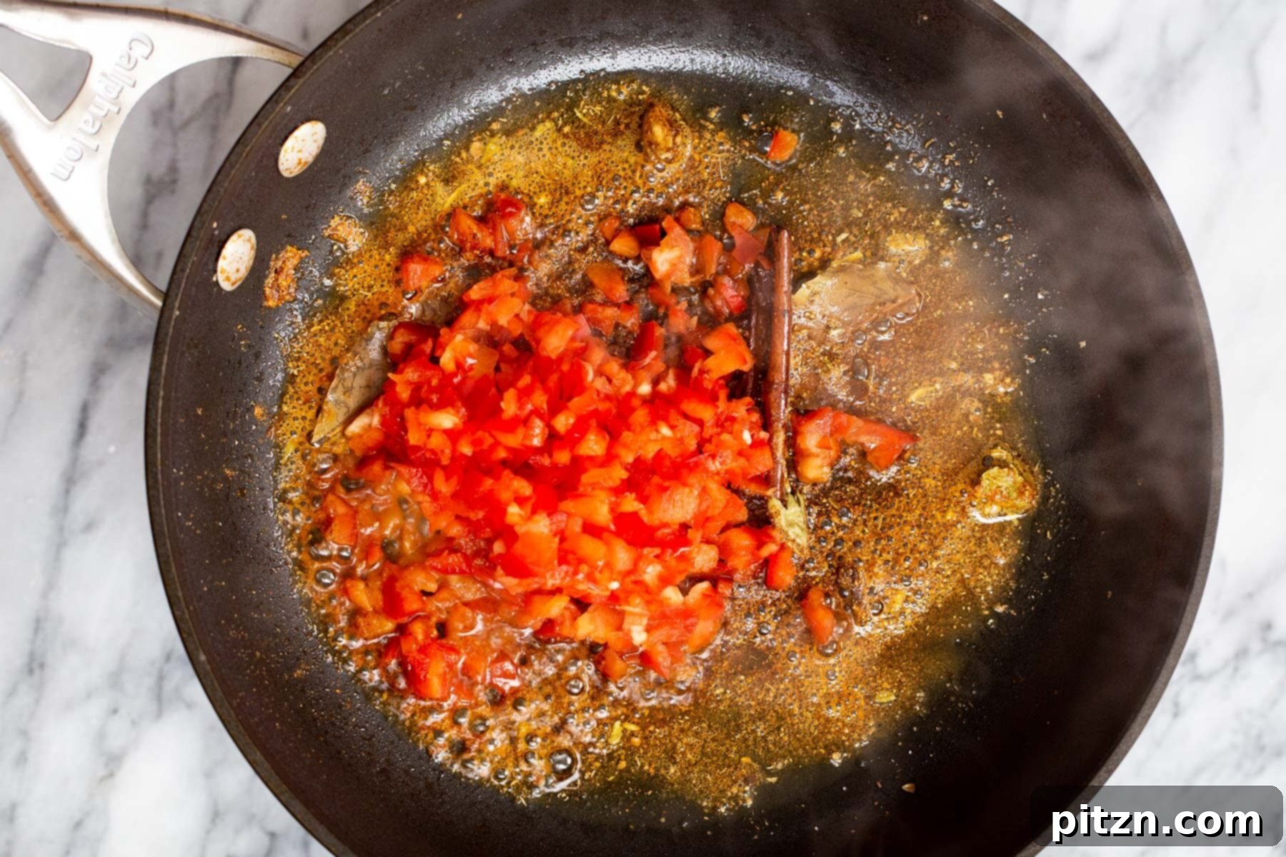 Vegan Tofu Rogan Josh 15 Finely chopped red bell pepper being added to the fragrant hot oil and spices in a frying pan.