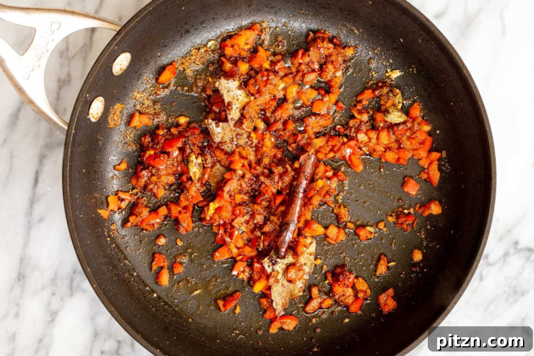 Vegan Tofu Rogan Josh 16 Chopped red bell pepper mixed with fried whole and ground spices in a sauté pan.