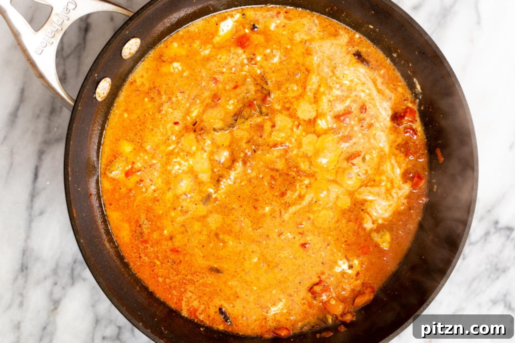 Vegan Tofu Rogan Josh 19 The creamy vegan Rogan Josh sauce simmering in a sauté pan, vibrant and rich with spices.