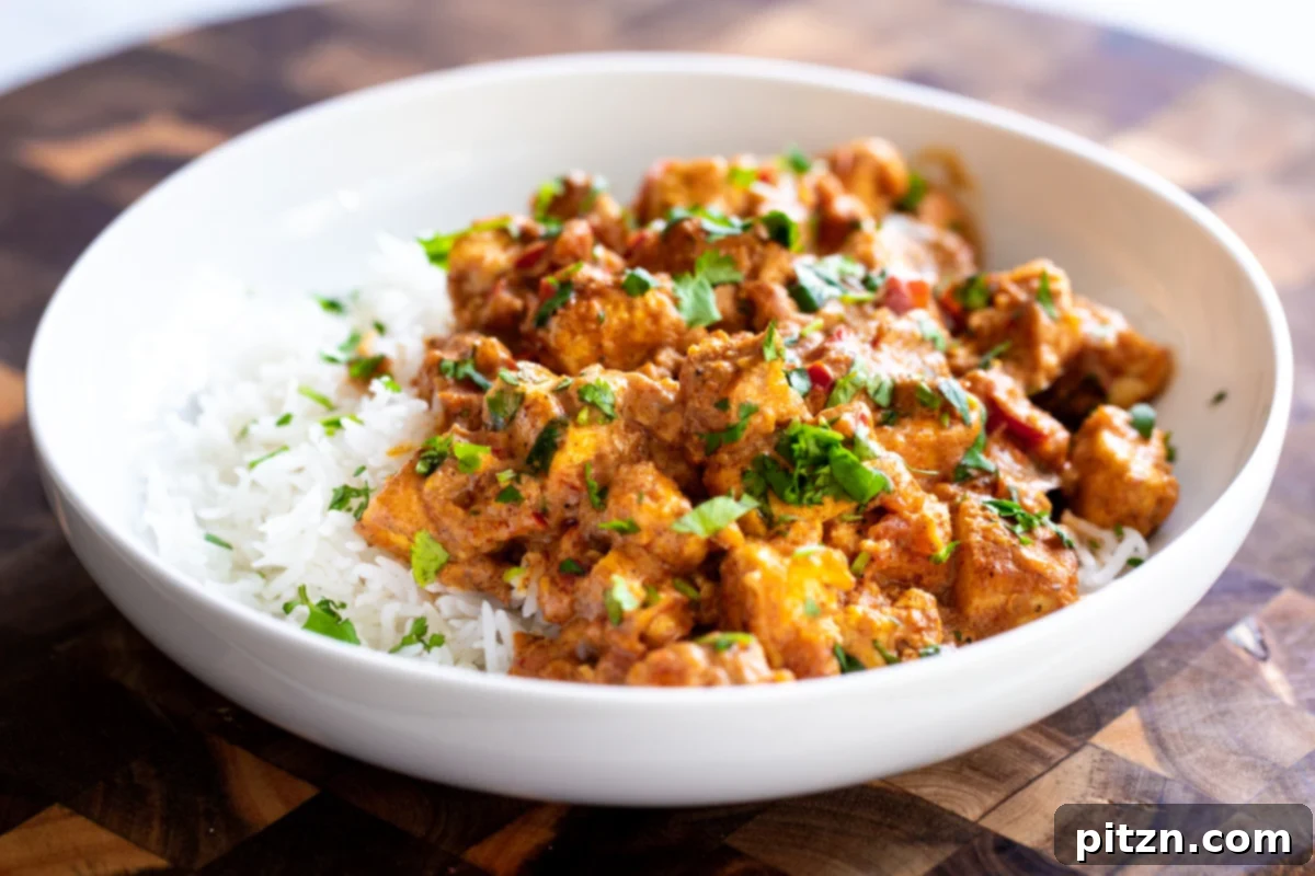 Vegan Tofu Rogan Josh 22 A vibrant plate of vegan tofu Rogan Josh served with fluffy rice, showcasing the rich color and inviting texture.