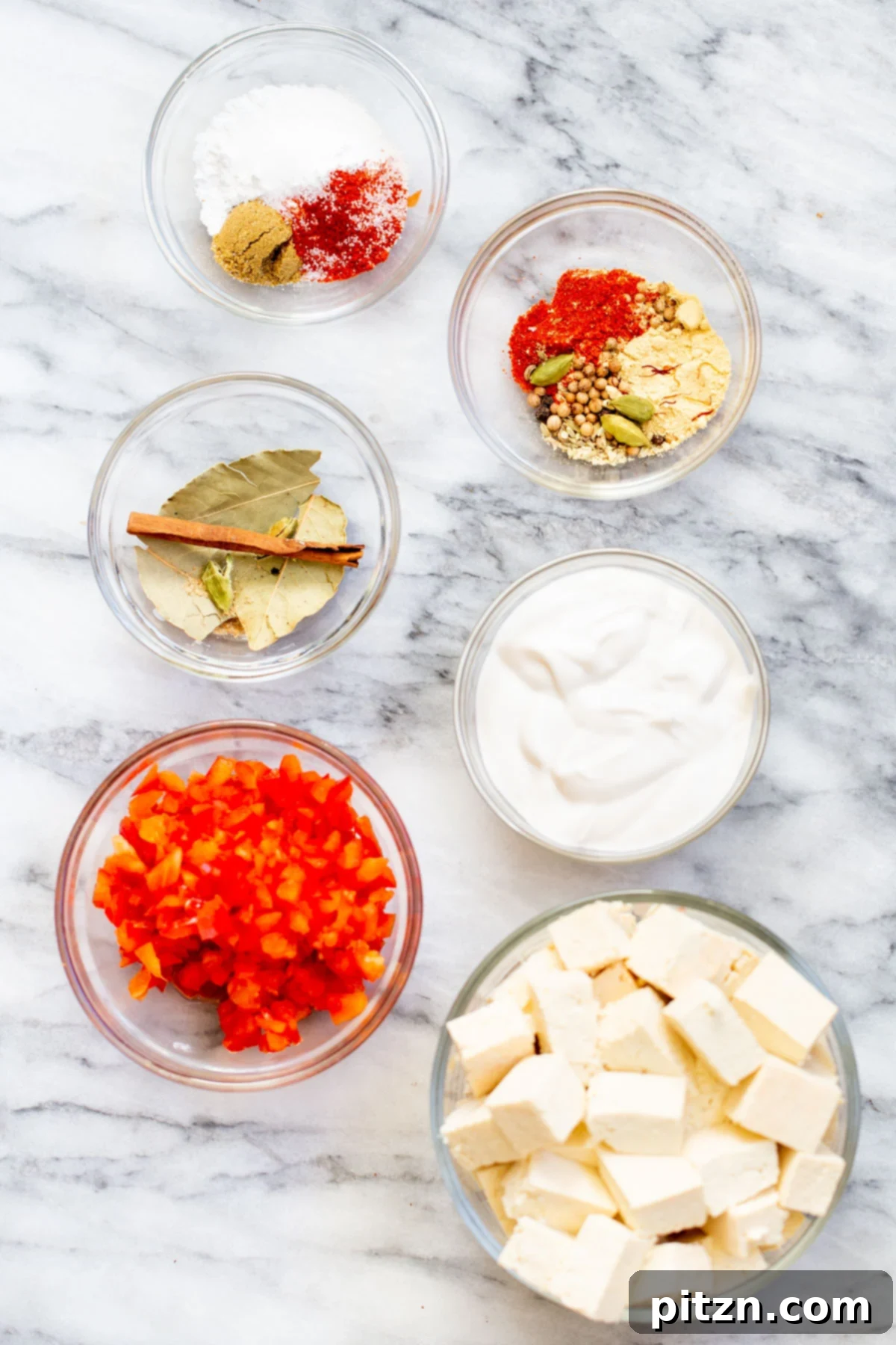 Vegan Tofu Rogan Josh 7 A collection of fresh ingredients laid out on a marble countertop, ready for making vegan Rogan Josh.