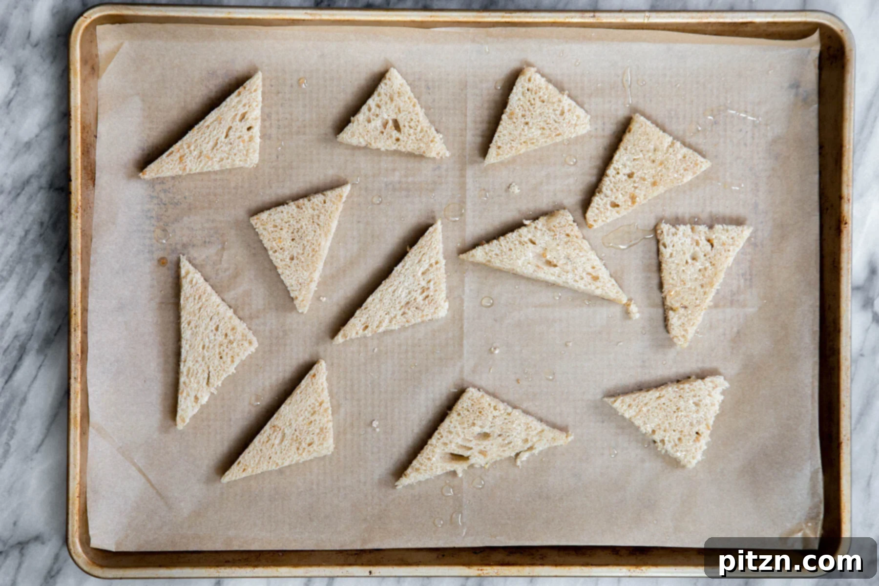 Shahi Tukda Royal Golden Toasts with Rabri Custard 7 Slices of bread brushed with vegan butter, arranged on a baking sheet, ready for toasting.