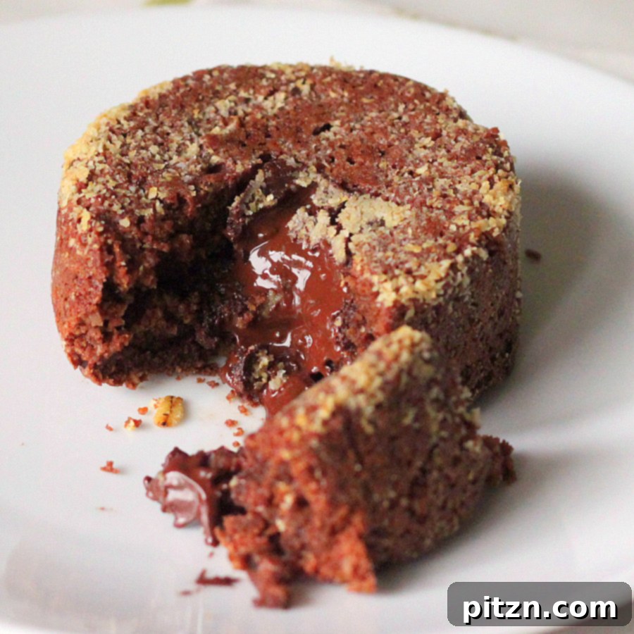 A beautifully presented molten lava cake on a white plate, with a spoon digging into its gooey center.