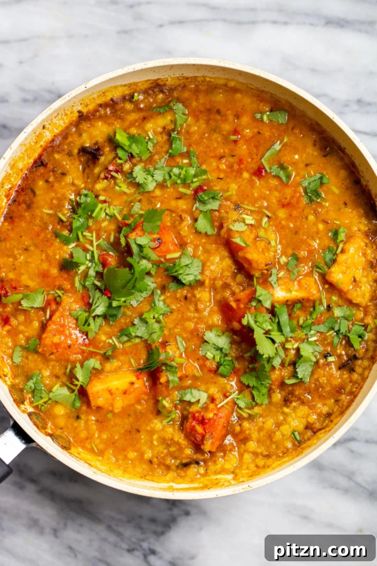 Creamy Plant-Based Dhaba Dal 16 A sautéing pan filled with red lentil butter dal, beautifully sprinkled with fresh cilantro