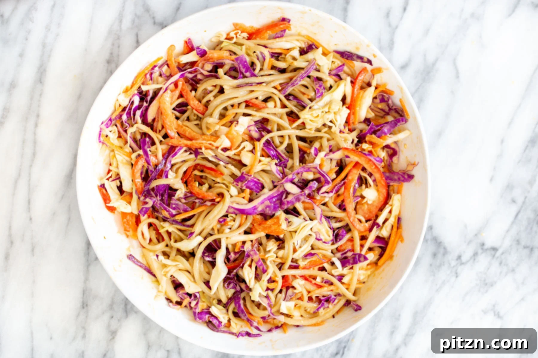 a white bowl with peanut sesame noodle salad, perfectly tossed