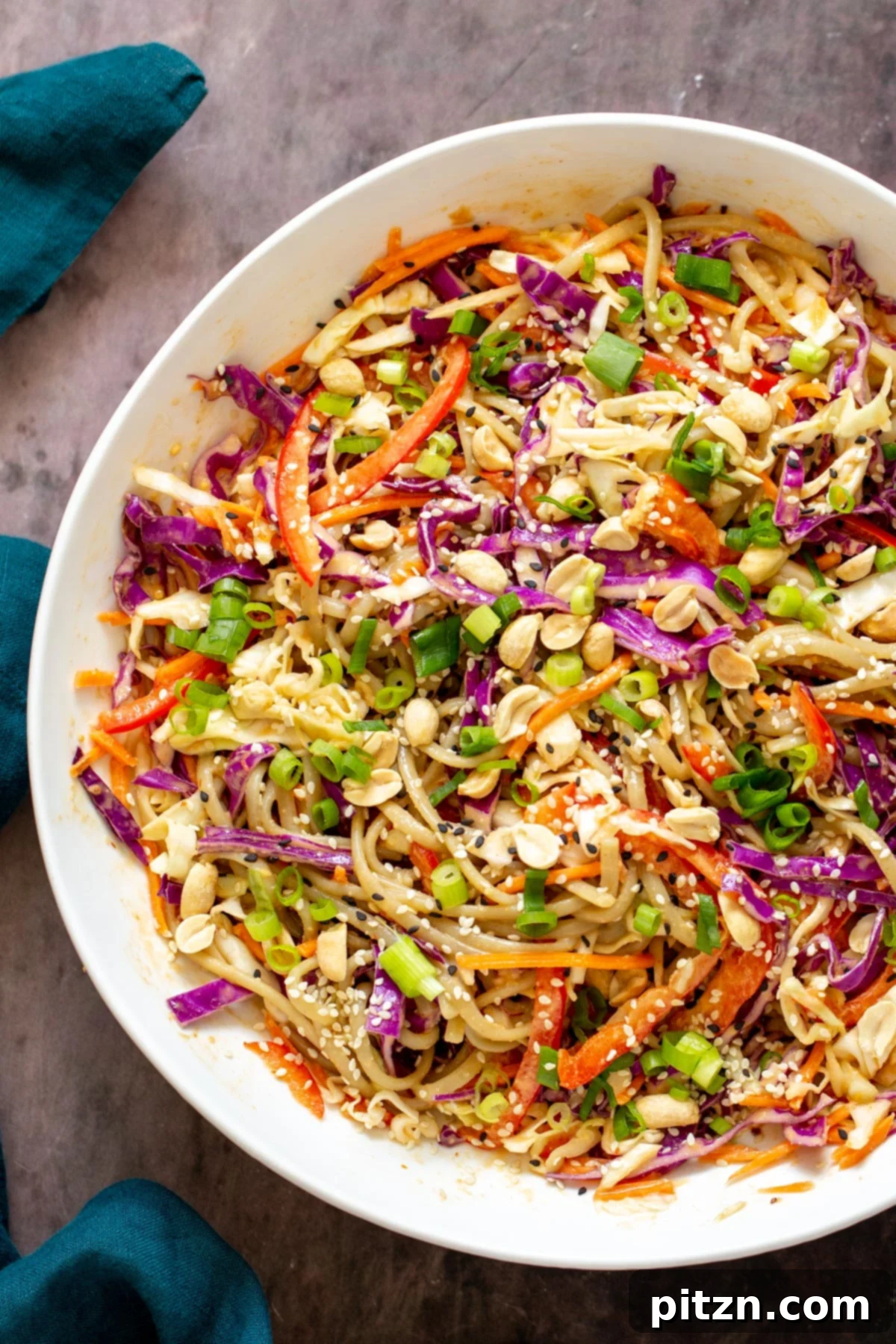 a bowl with peanut sesame noodle salad tossed with a creamy peanut dressing, ready to be served