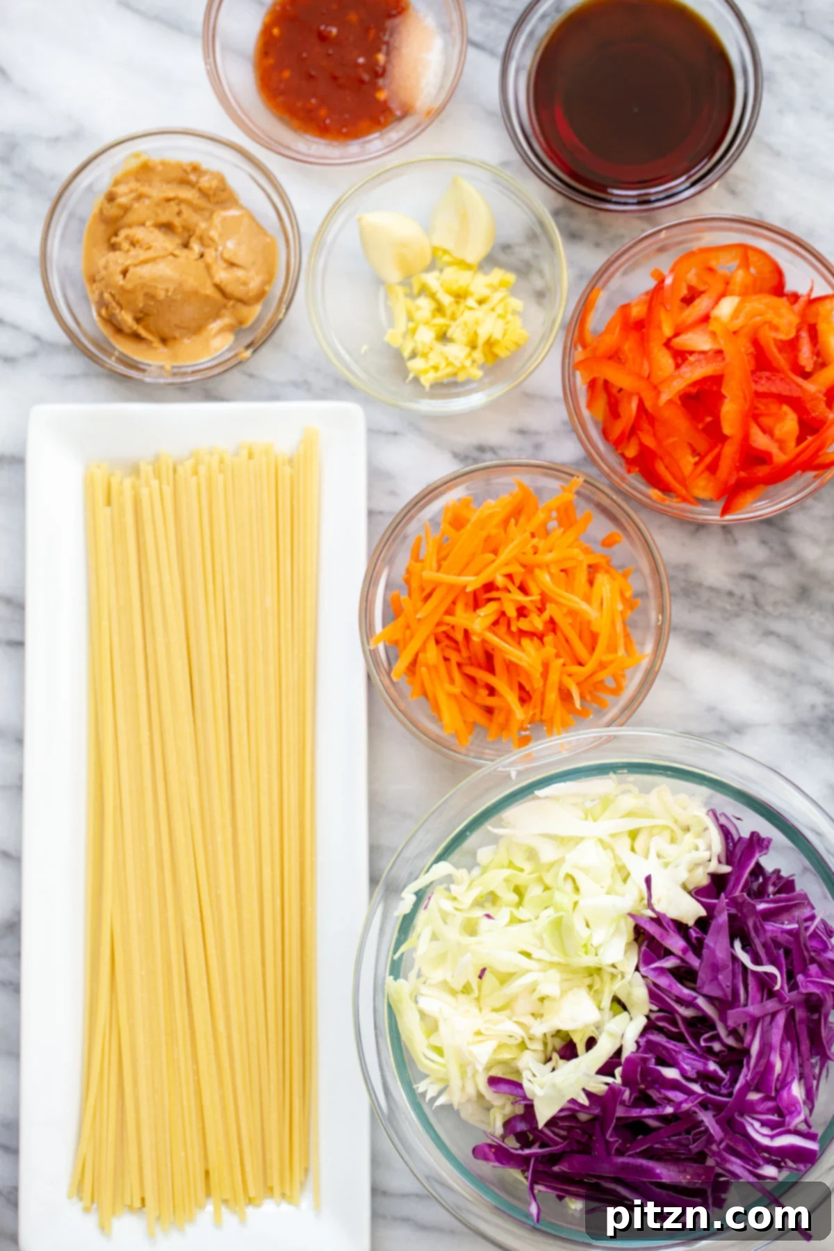 ingredients used for making peanut sesame noodle salad laid out on a wooden board