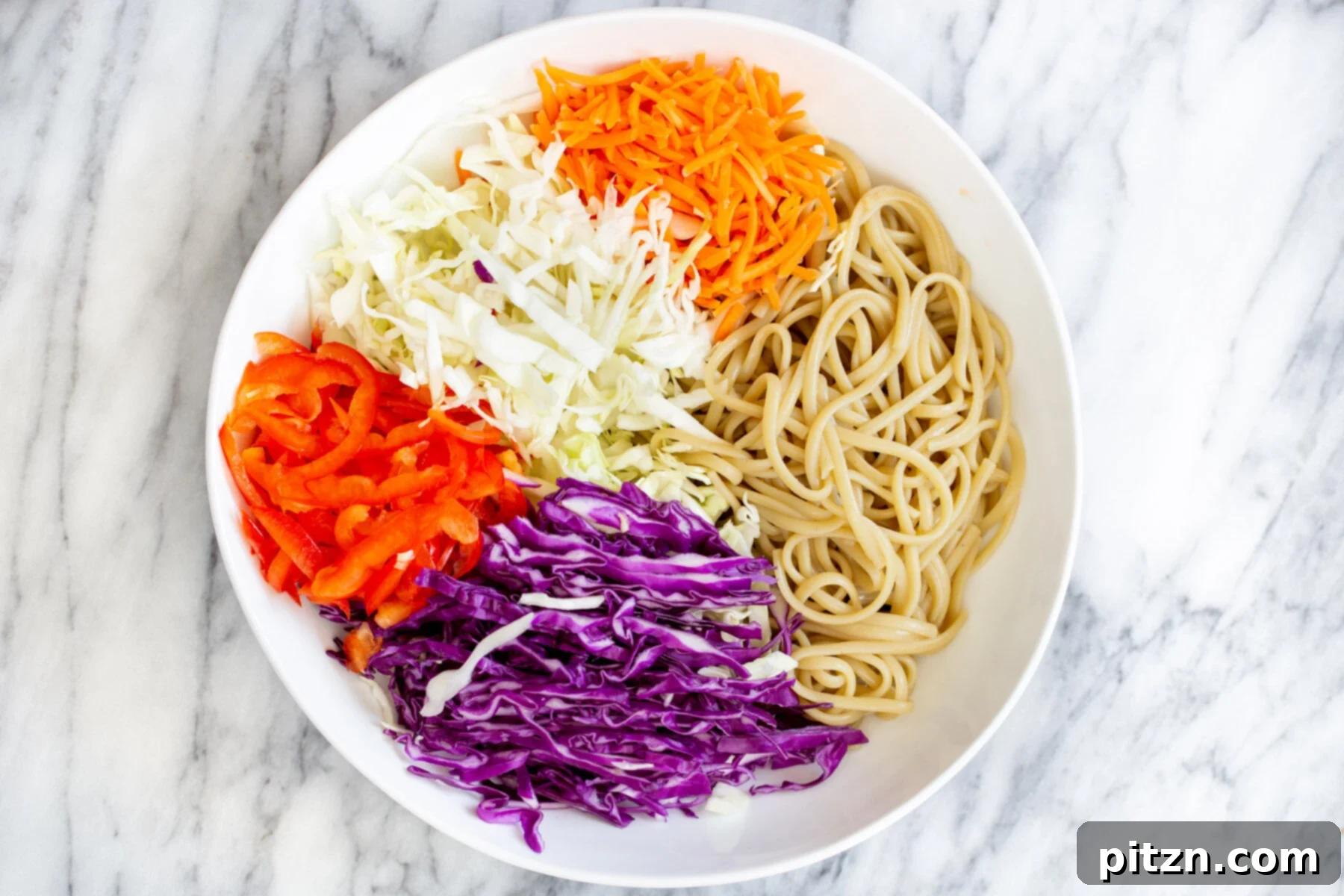 peanut sesame noodle salad ingredients in a white bowl, ready for blending