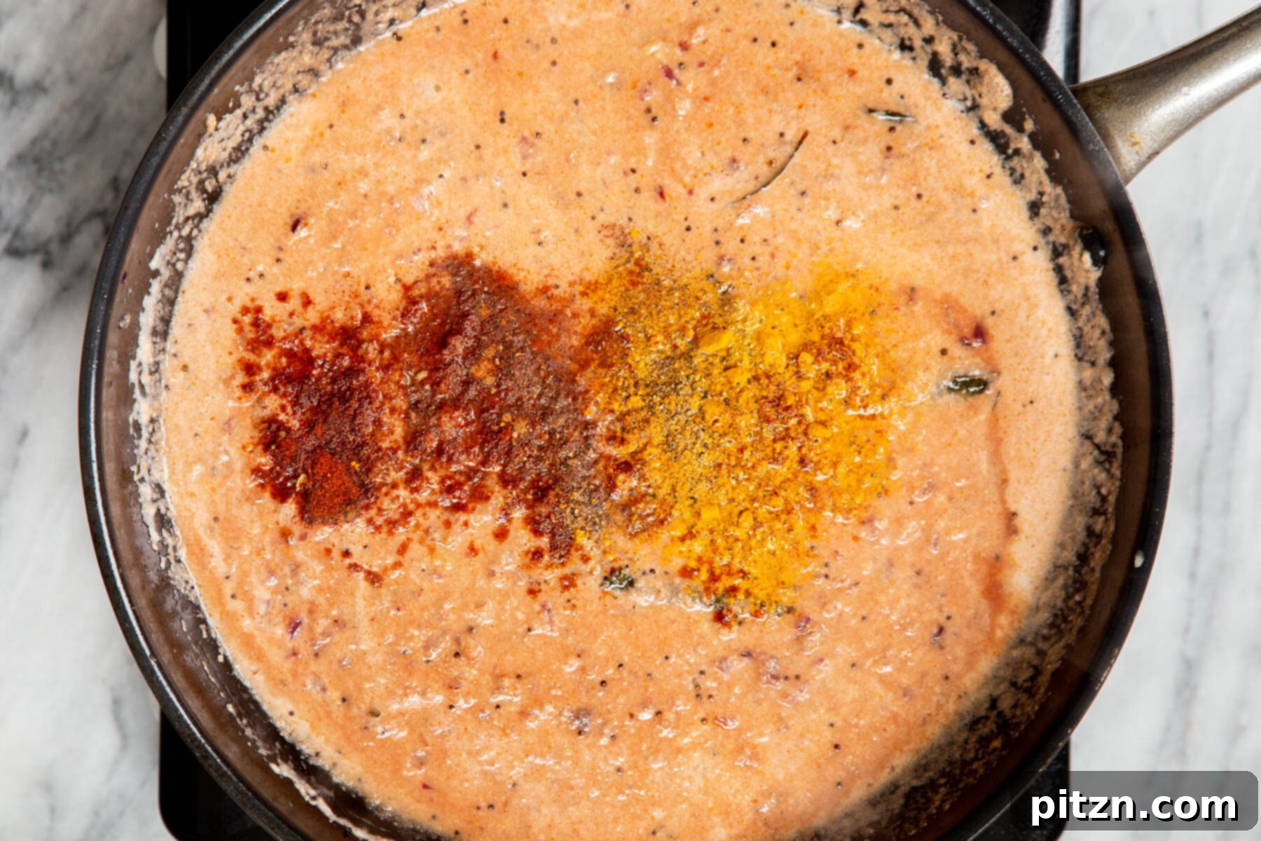 Hearty Vegan Malabar Curry 15 Freshly ground spices being added to the rich Malabar curry gravy in a pan.
