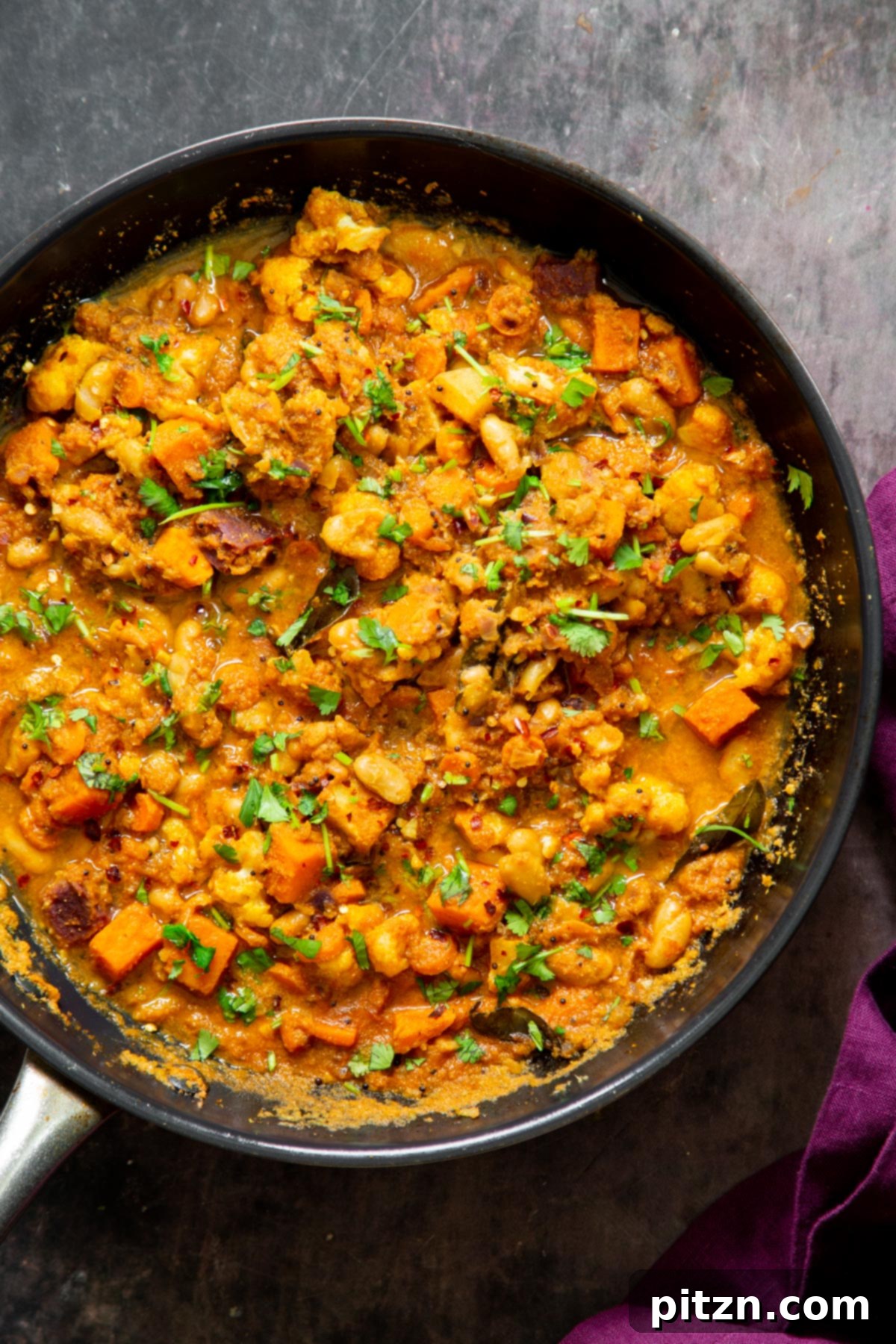 Hearty Vegan Malabar Curry 18 A large skillet filled with vegan Malabar curry, showcasing the rich gravy and tender, colorful vegetables.