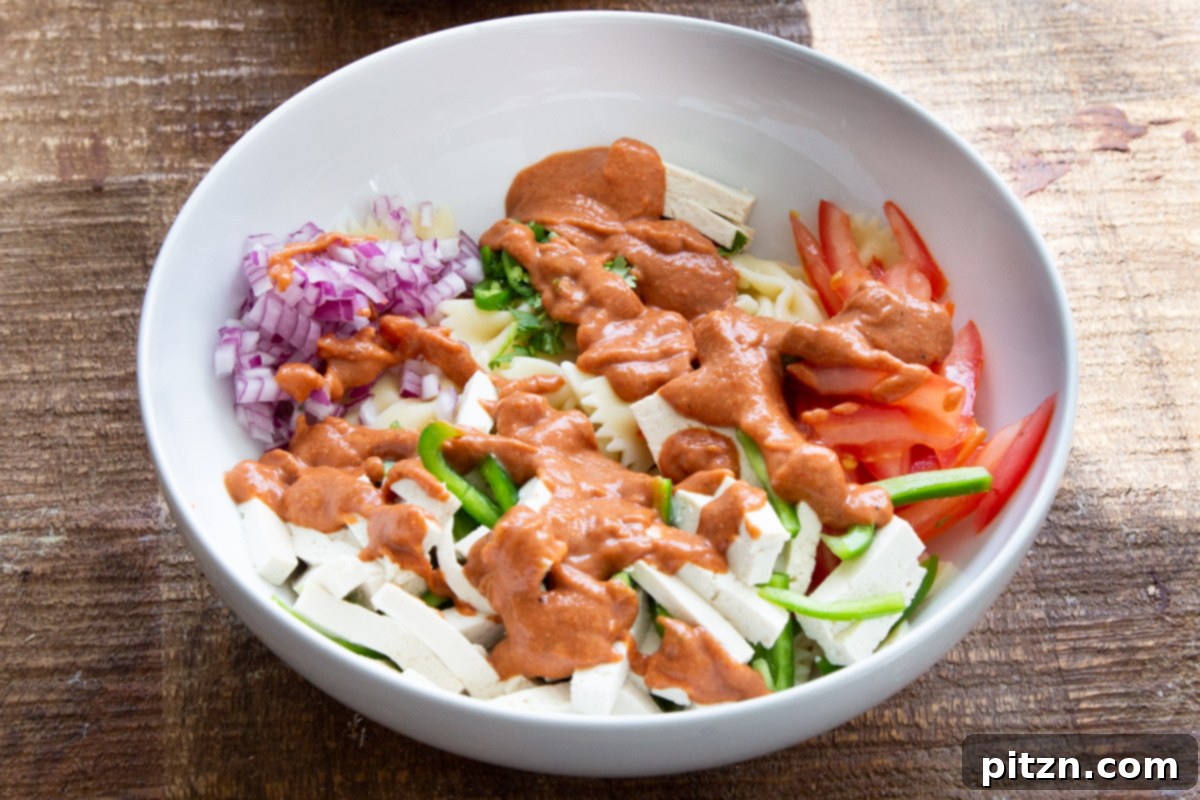 Fusion Tikka Pasta Salad 12 Creamy Tikka Masala dressing drizzled over pasta salad ingredients in a white bowl
