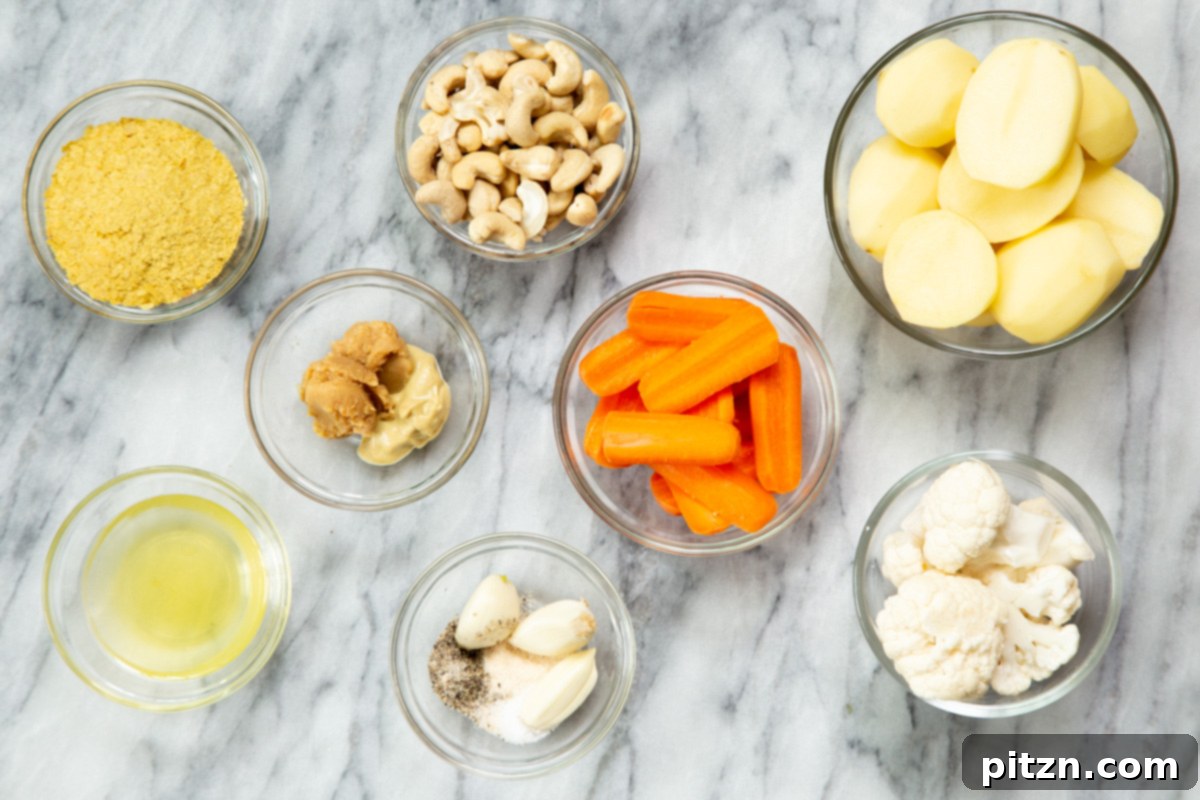 A collection of fresh ingredients, including potatoes, carrots, cauliflower, cashews, and spices, laid out for making vegan cheese sauce in the Instant Pot.