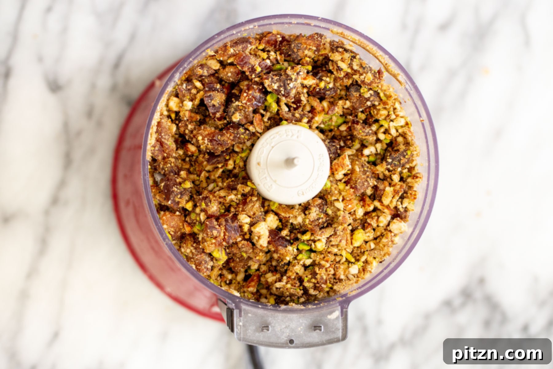 The perfect blend of chopped nuts and dates in a small food processor, forming a delicious, sticky mixture.