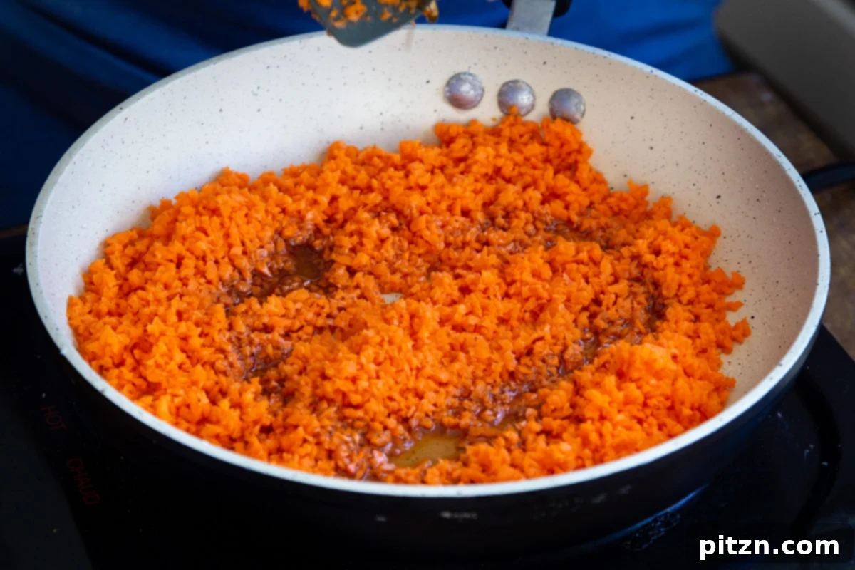 Layered Vegan Carrot Halwa Coconut Burfi 13 shredded carrots and maple syrup in a sauteeing pan