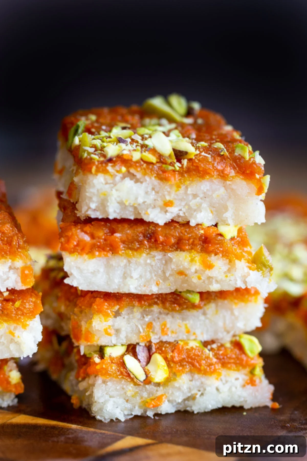 Layered Vegan Carrot Halwa Coconut Burfi 5 a stack of carrot halwa coconut burfi bars topped with pistachios