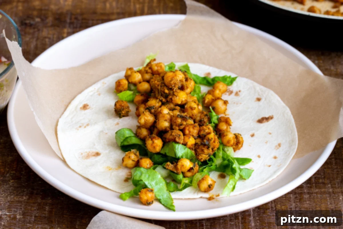 Tangy Chickpea Wraps 10 A warm wheat tortilla layered with crisp chopped lettuce and a generous scoop of spiced chickpeas, ready for the next layer of toppings.
