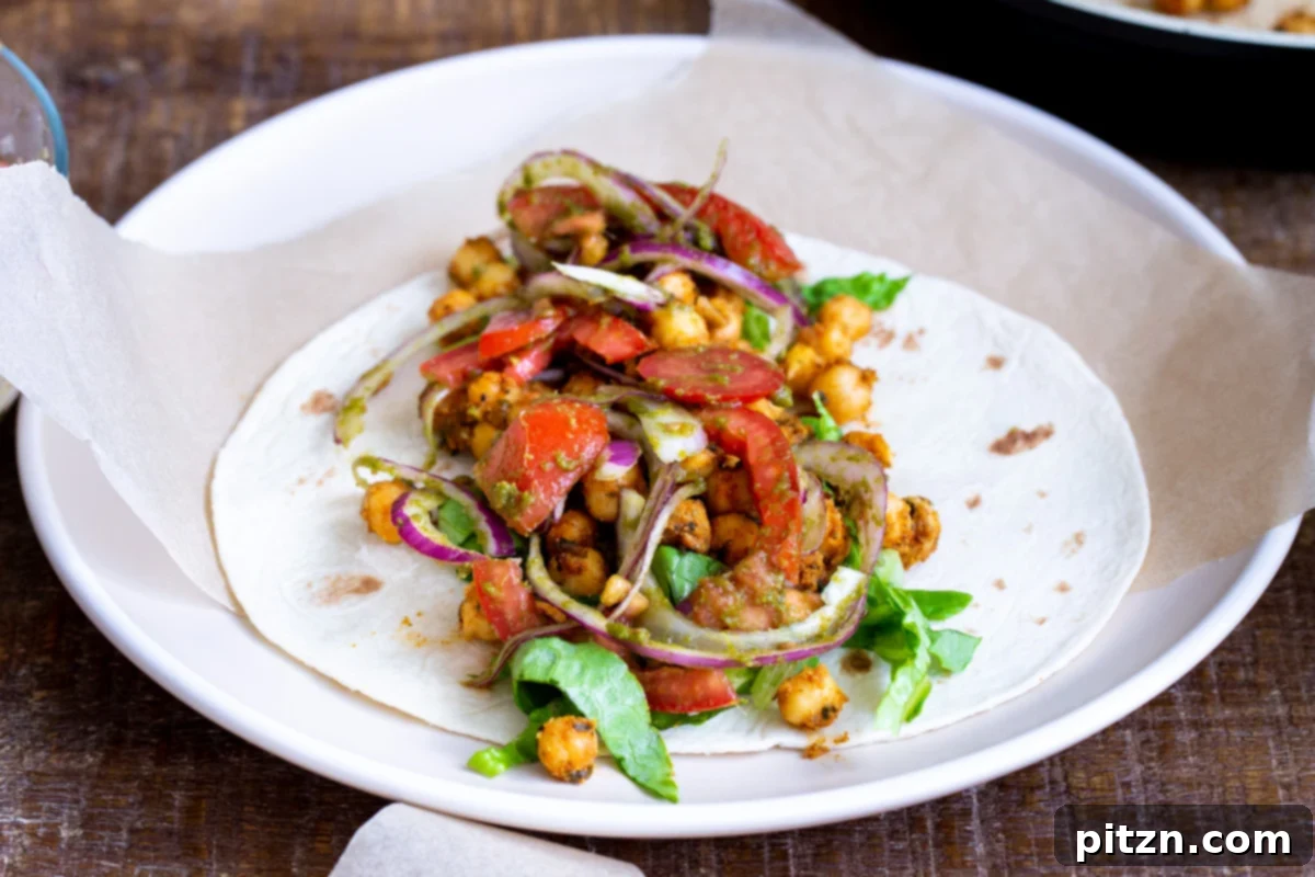 Tangy Chickpea Wraps 11 A selection of Indian chickpea Kathi Rolls, fully loaded with chickpeas, tomatoes, onions, and lettuce, poised for rolling and serving.