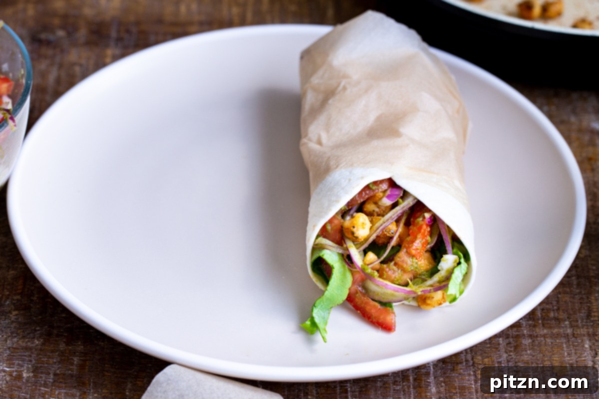 Tangy Chickpea Wraps 12 A freshly wrapped chickpea Kathi Roll, showing its neatly tucked ends, presented on a plate, ready to be enjoyed.